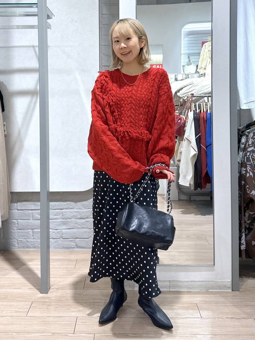 ブラック系のスカート、レッド系のポロシャツ、ブラック系のブーツを着用したレディースの冬コーディネートの2枚目の写真