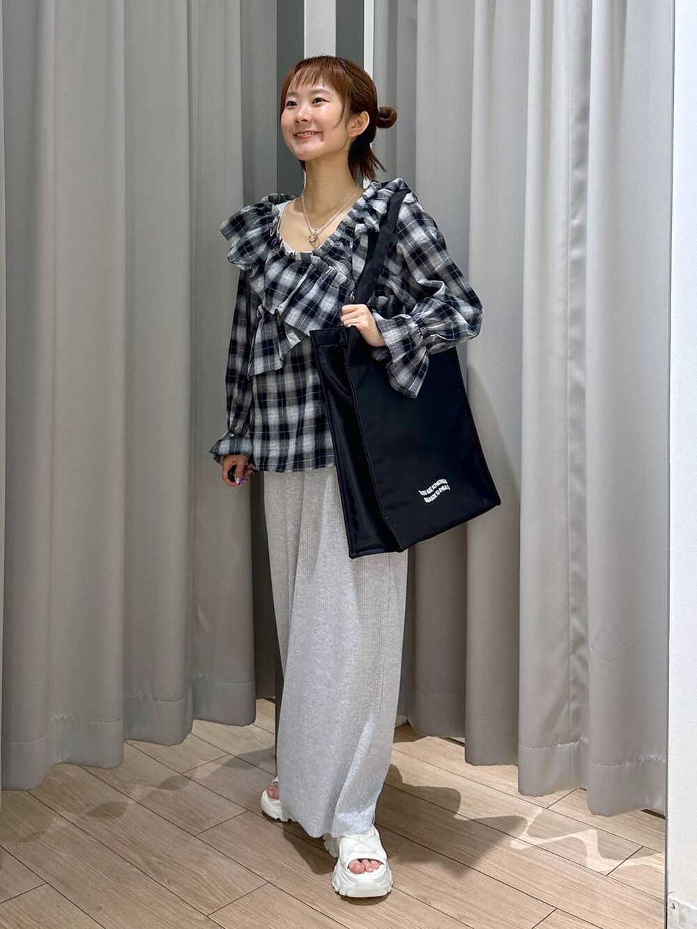 グレー系のスカート、ホワイト系のサンダル、ブラック系のトートバッグを着用したレディースの夏コーディネートの3枚目の写真