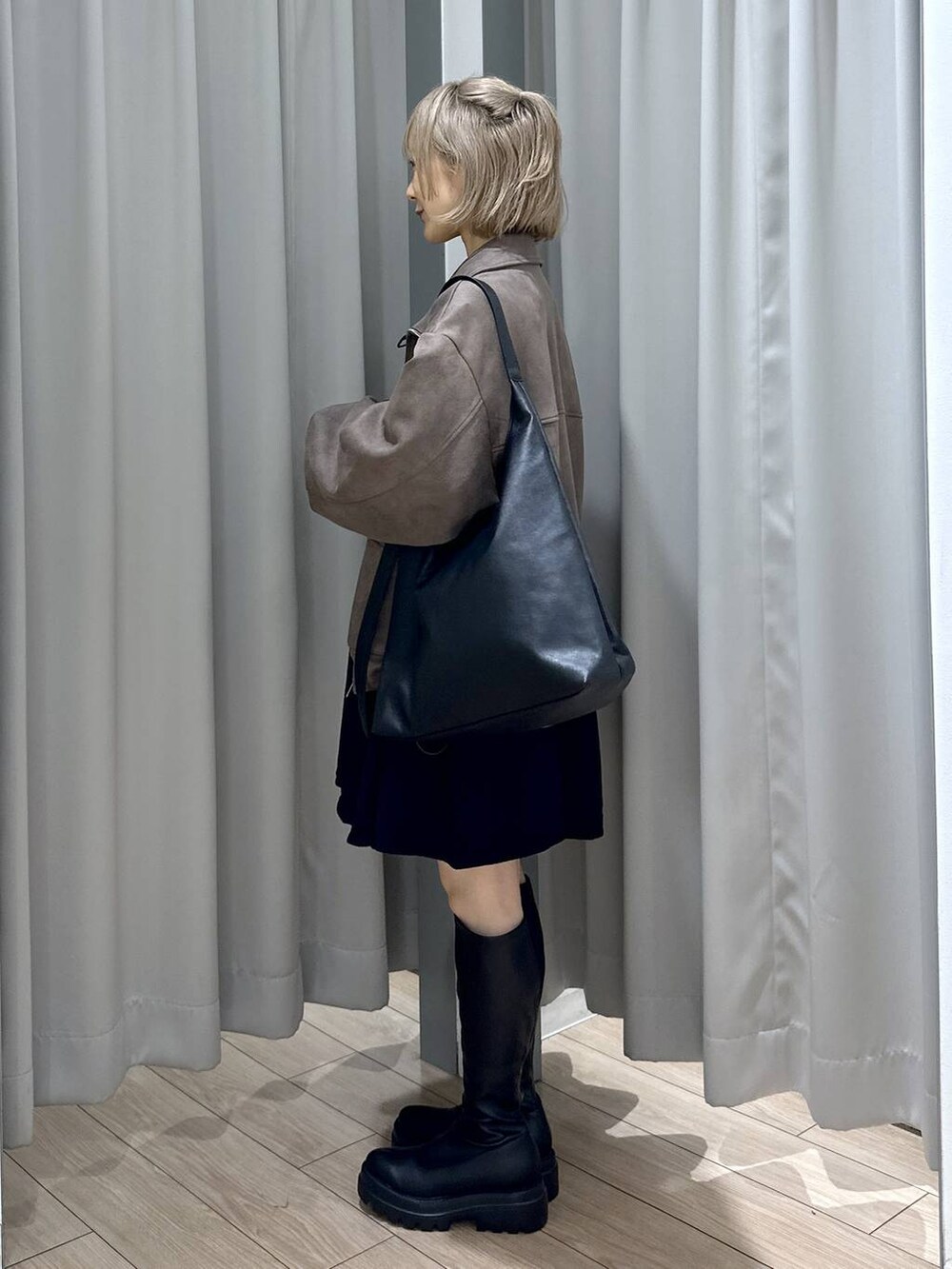 ブラック系のショルダーバッグ、ブラウン系のブルゾン、ブラック系のブーツを着用したレディースの秋コーディネートの2枚目の写真