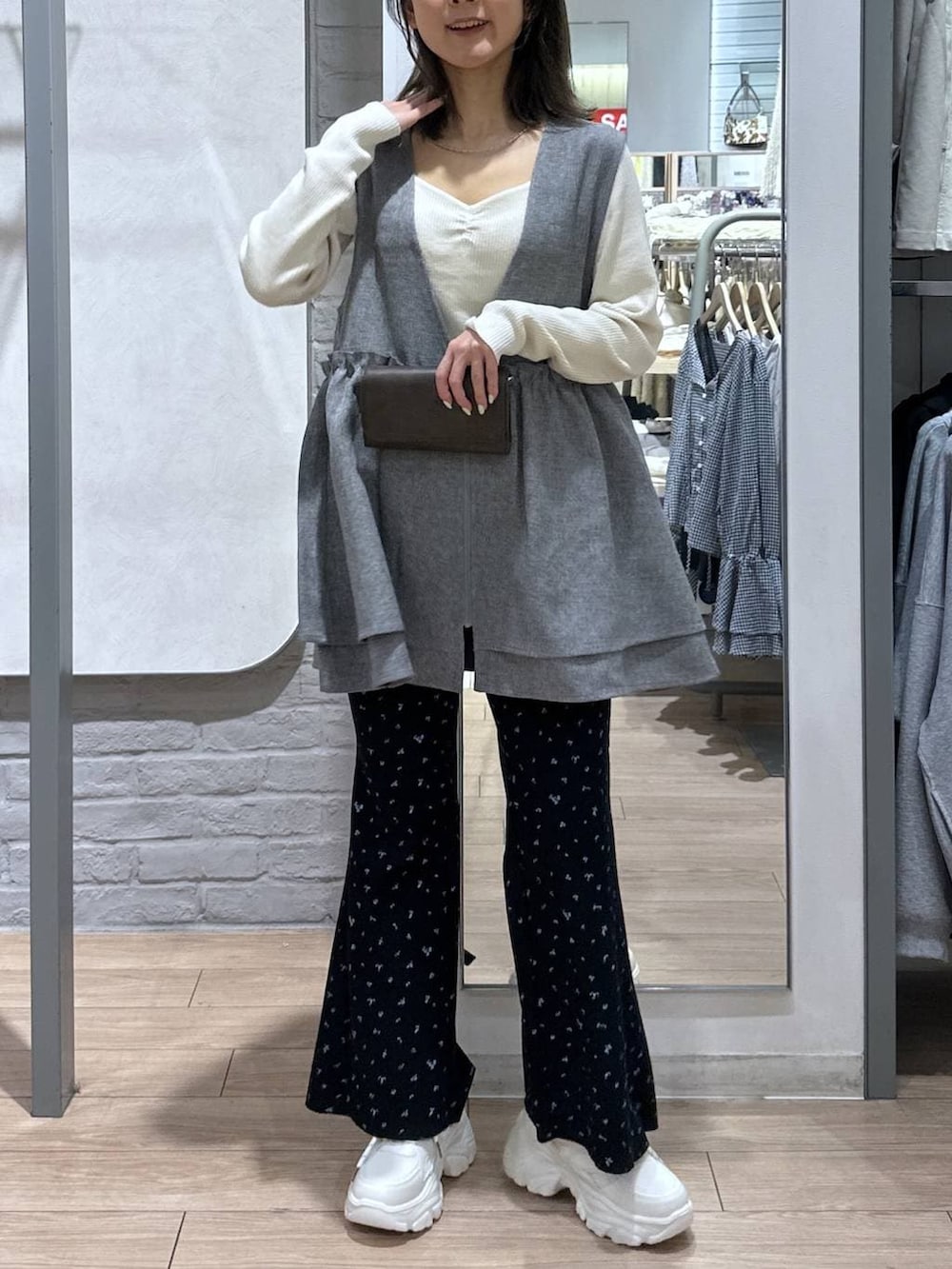 グレー系のベスト、ホワイト系のニット/セーター、ブラック系のボディバッグ/ウエストポーチを着用したレディースの春コーディネートの2枚目の写真