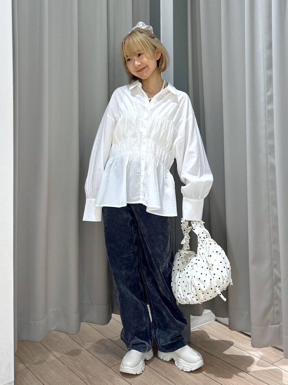 ホワイト系のブーツ、グレー系のデニムパンツ、ホワイト系のショルダーバッグを着用したレディースの秋コーディネートの2枚目の写真