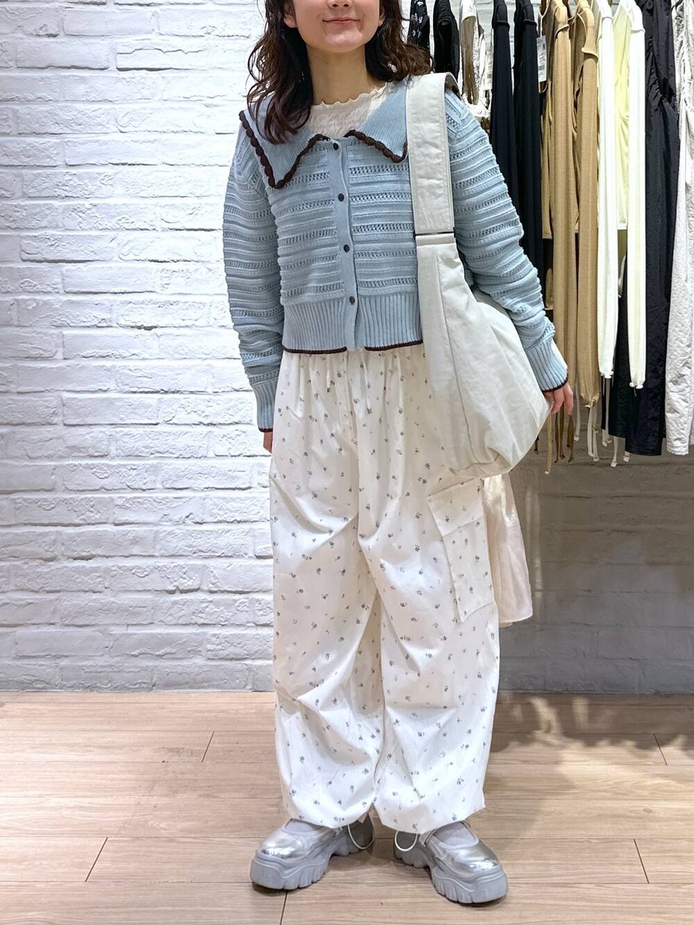 ベージュ系のショルダーバッグ、ホワイト系のTシャツ/カットソー、ブルー系のニット/セーターを着用したレディースの春コーディネートの4枚目の写真