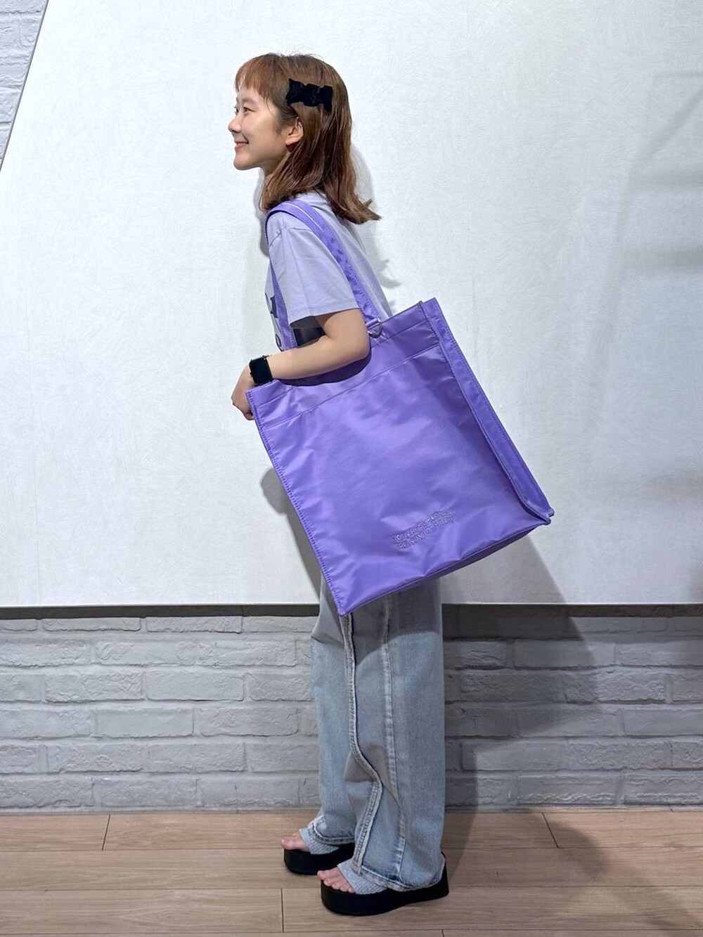 シルバー系のサンダル、パープル系のトートバッグ、ブルー系のデニムパンツを着用したレディースの夏コーディネートの2枚目の写真