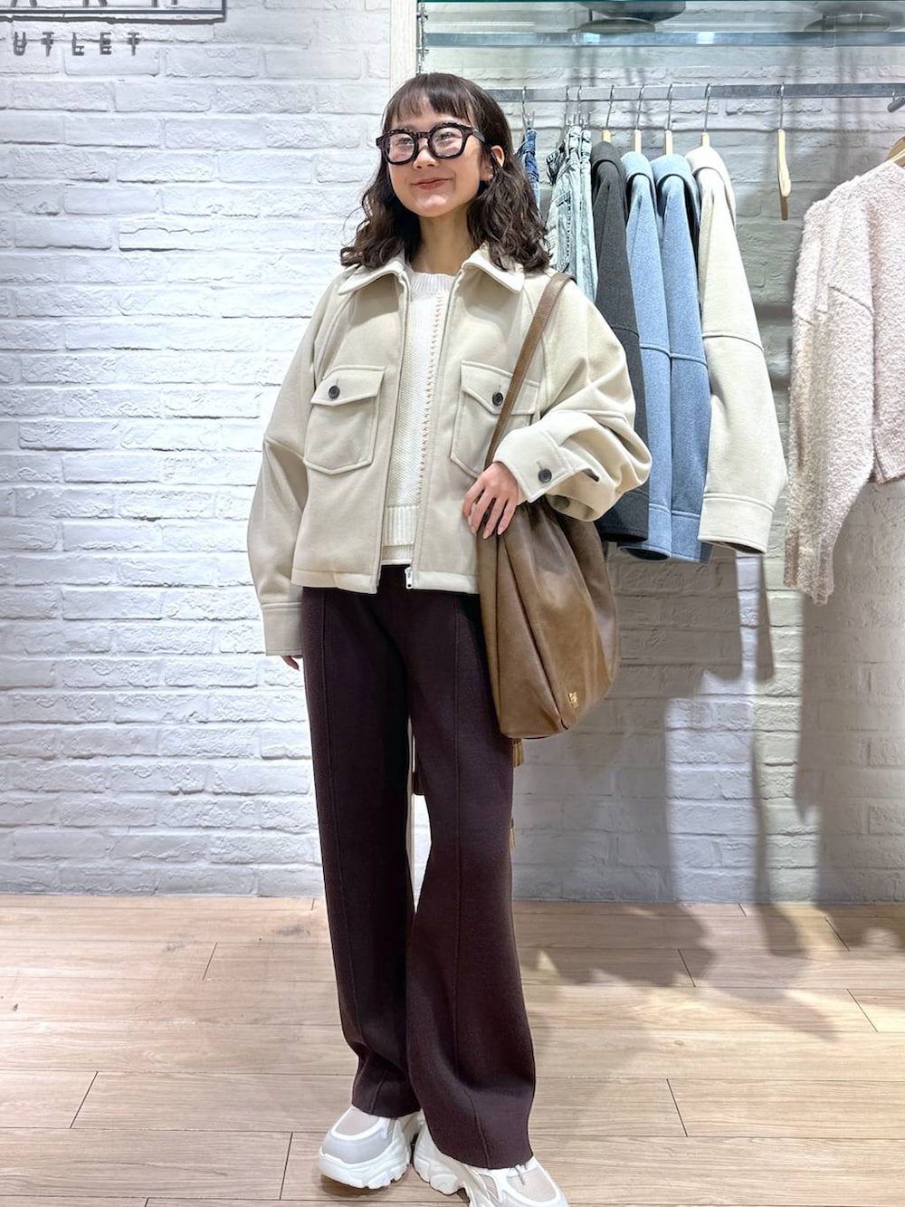 ホワイト系のニット/セーター、ベージュ系のスニーカー、ブラウン系のショルダーバッグを着用したレディースの冬コーディネートの3枚目の写真