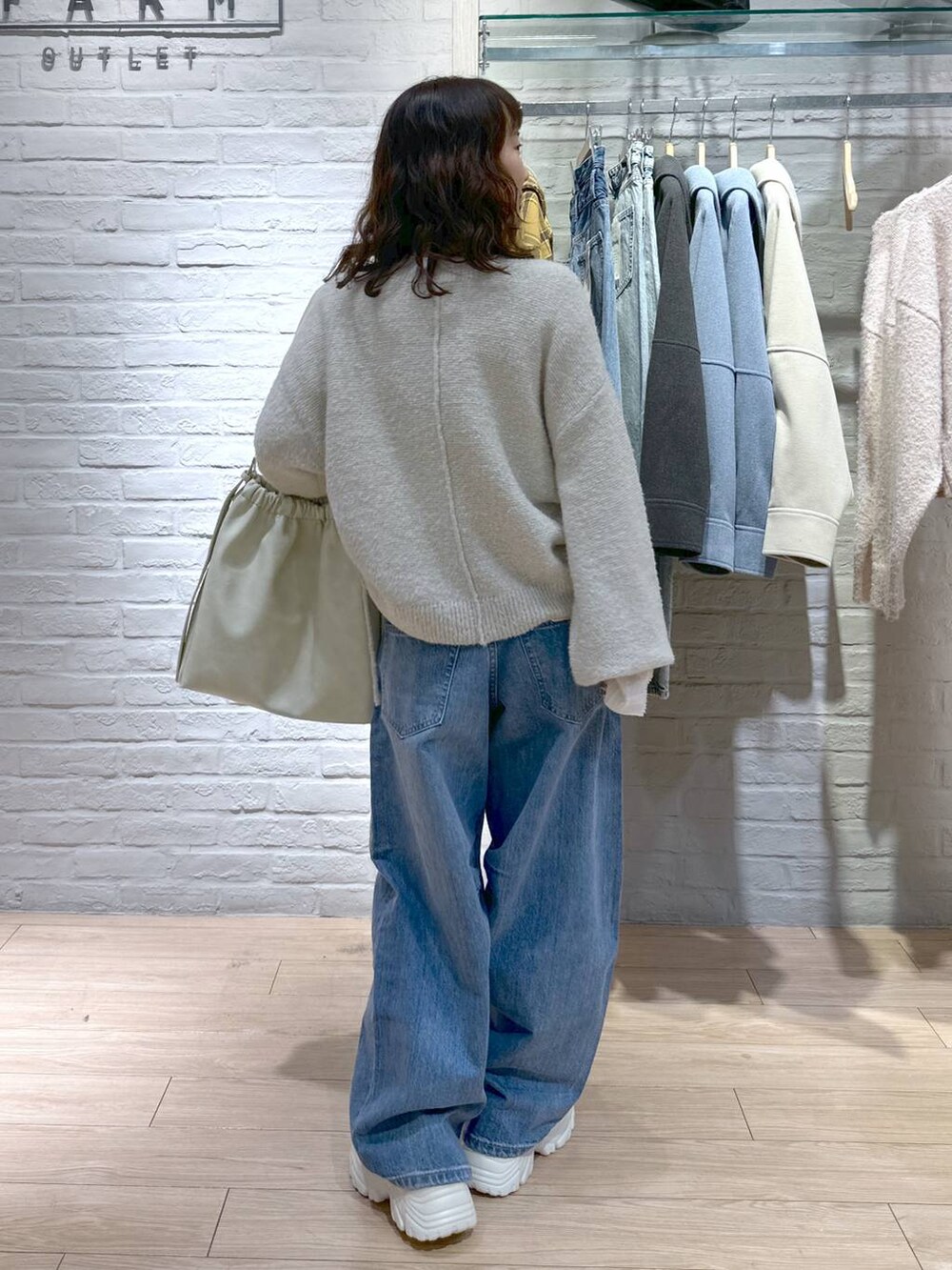 ブルー系のデニムパンツ、ホワイト系のショルダーバッグ、ベージュ系のスニーカーを着用したレディースの冬コーディネートの5枚目の写真