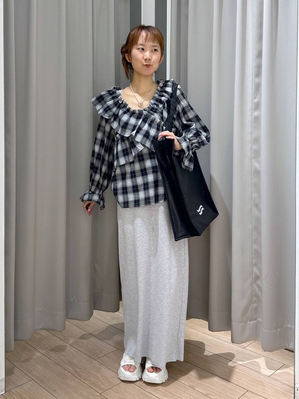 グレー系のスカート、ホワイト系のサンダル、ブラック系のトートバッグを着用したレディースの夏コーディネートの5枚目の写真