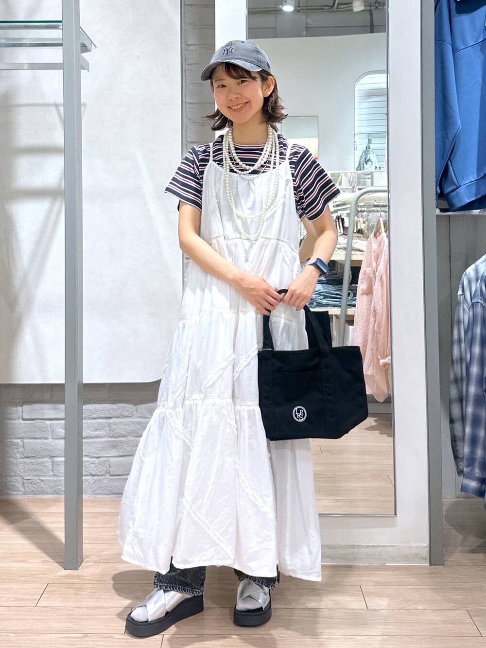 ブルー系のTシャツ/カットソー、ブラック系のデニムパンツ、ブラック系のショルダーバッグを着用したレディースの春コーディネートの4枚目の写真