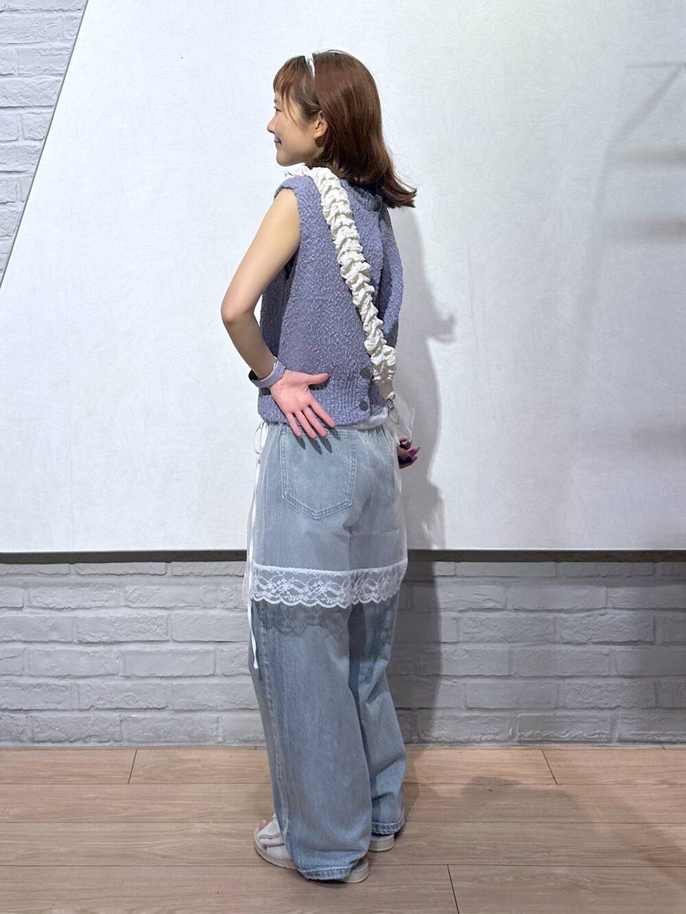 ホワイト系のサンダル、パープル系のベスト、ブルー系のデニムパンツを着用したレディースの夏コーディネートの2枚目の写真