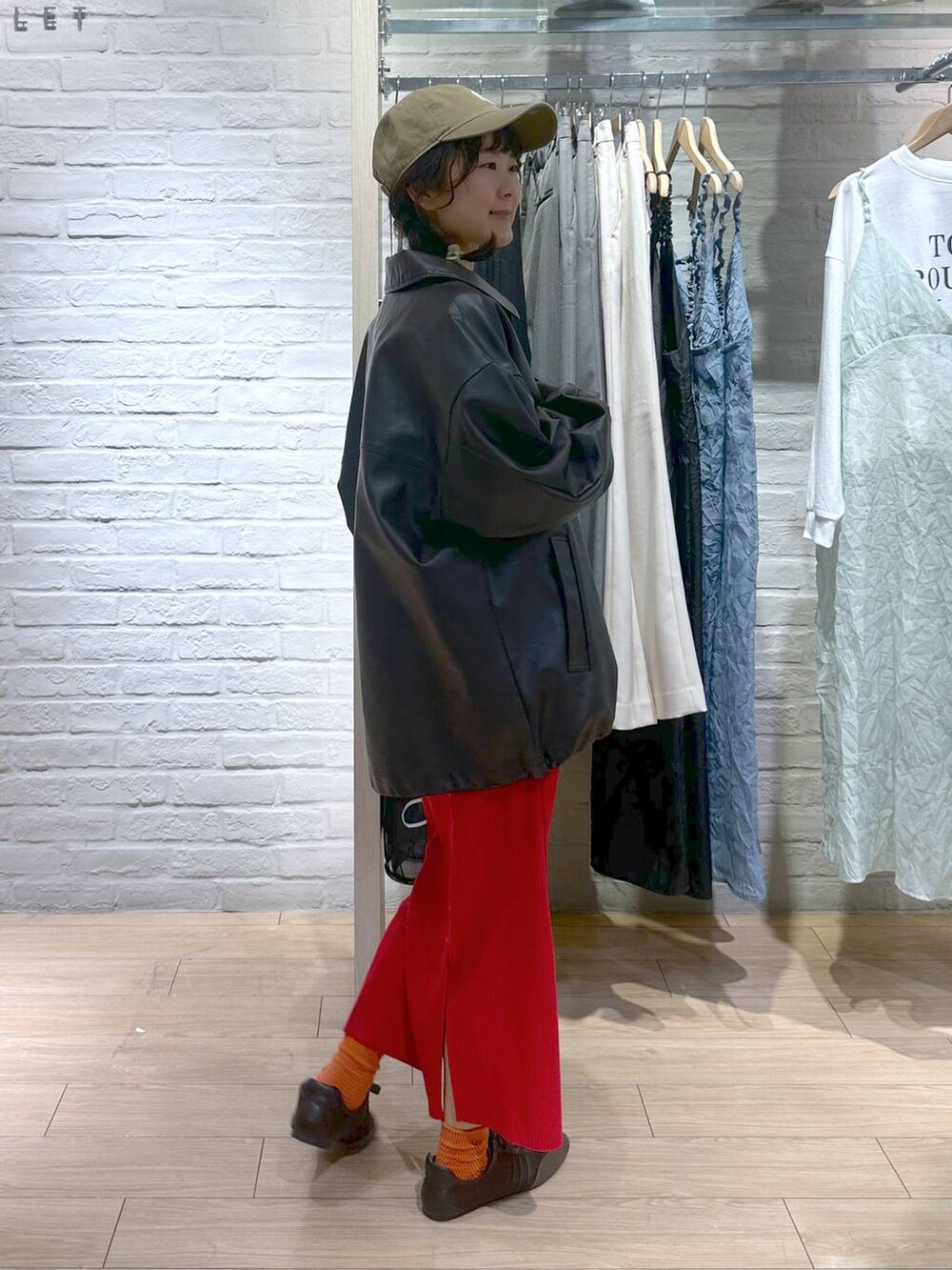 レッド系のスカート、ブラウン系のブルゾン、ホワイト系のスウェットを着用したレディースの春コーディネートの4枚目の写真