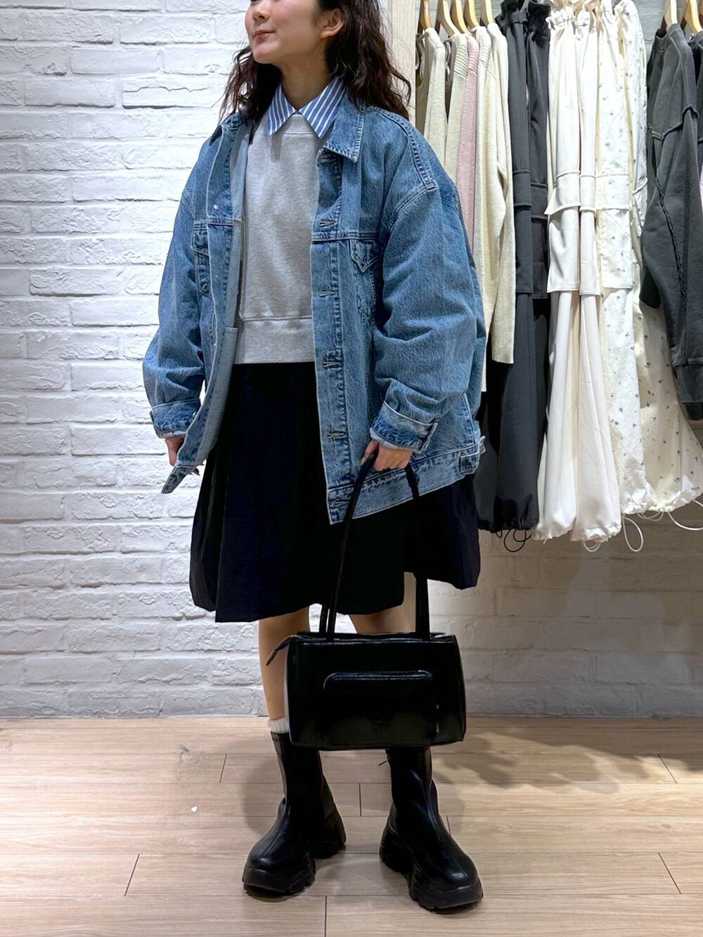 ブルー系のデニムジャケット、ブラック系のショルダーバッグ、ブラック系のブーツを着用したレディースの春コーディネートの2枚目の写真