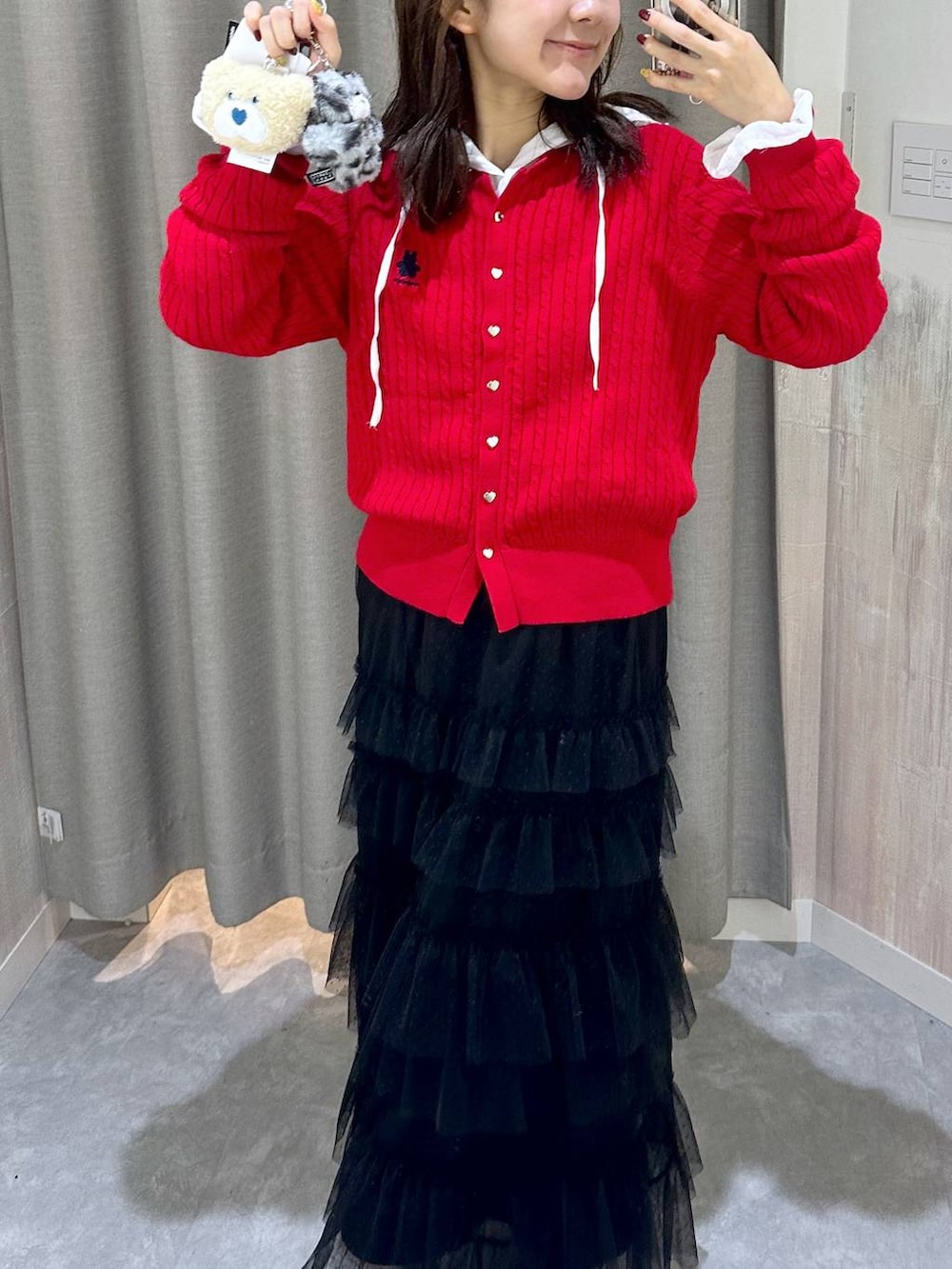 レッド系のカーディガン/ボレロ、ブラック系のスカート、ホワイト系のシャツ/ブラウスを着用したレディースの秋コーディネートの3枚目の写真