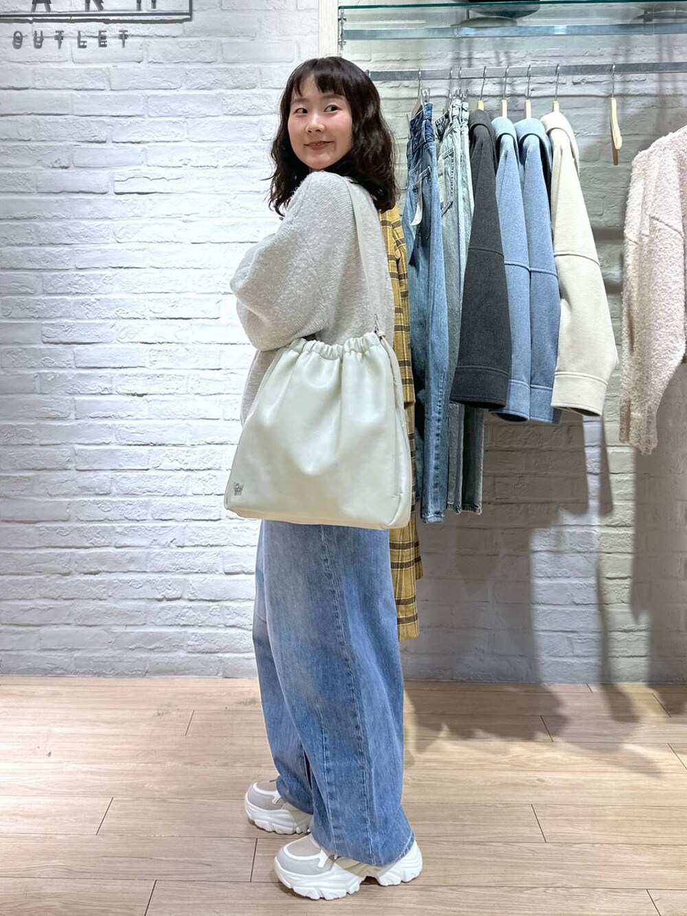 ブルー系のデニムパンツ、ホワイト系のショルダーバッグ、ベージュ系のスニーカーを着用したレディースの冬コーディネートの3枚目の写真