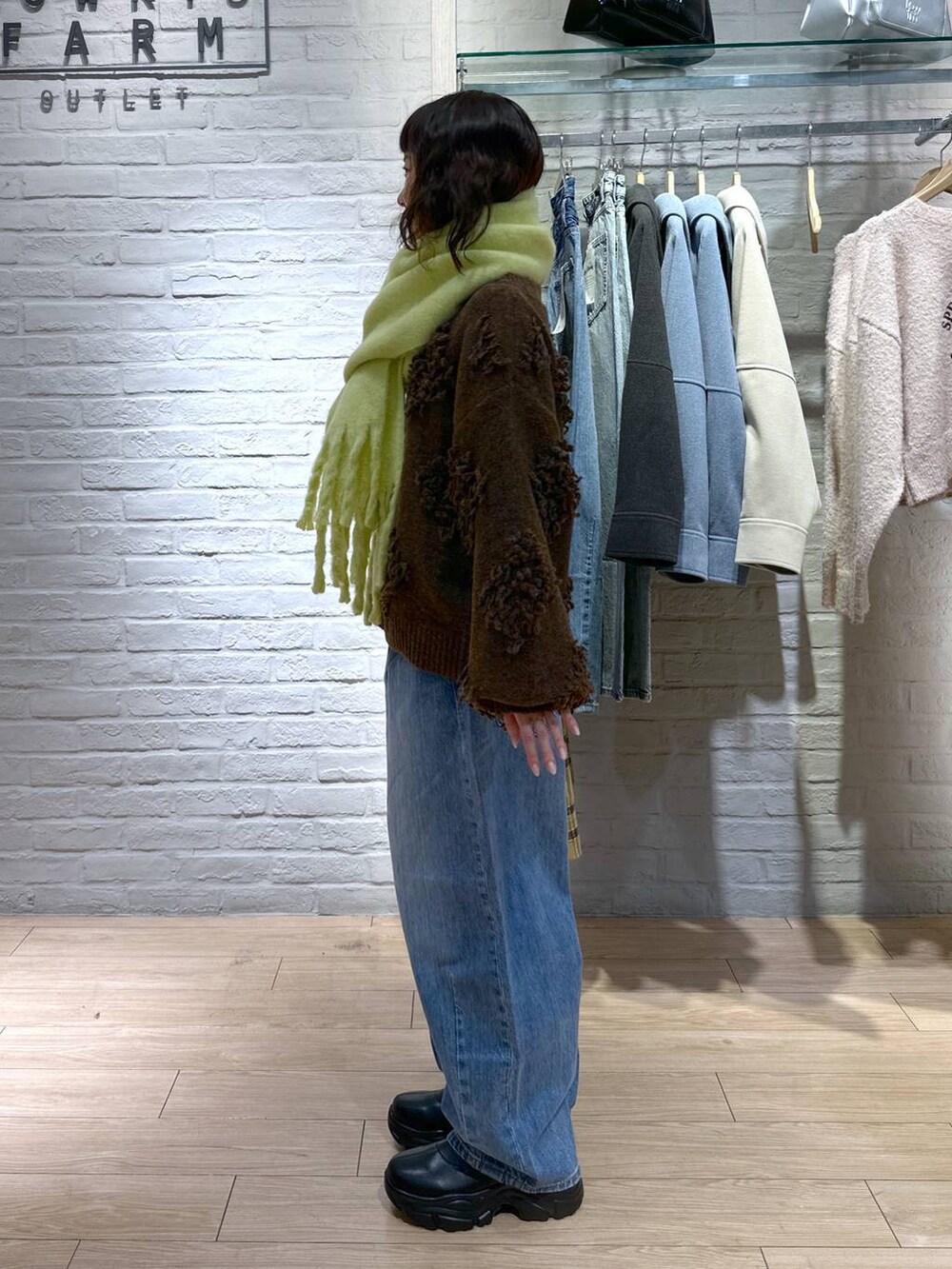 ブルー系のデニムパンツ、ブラック系のブーツ、ブラウン系のトートバッグを着用したレディースの冬コーディネートの3枚目の写真