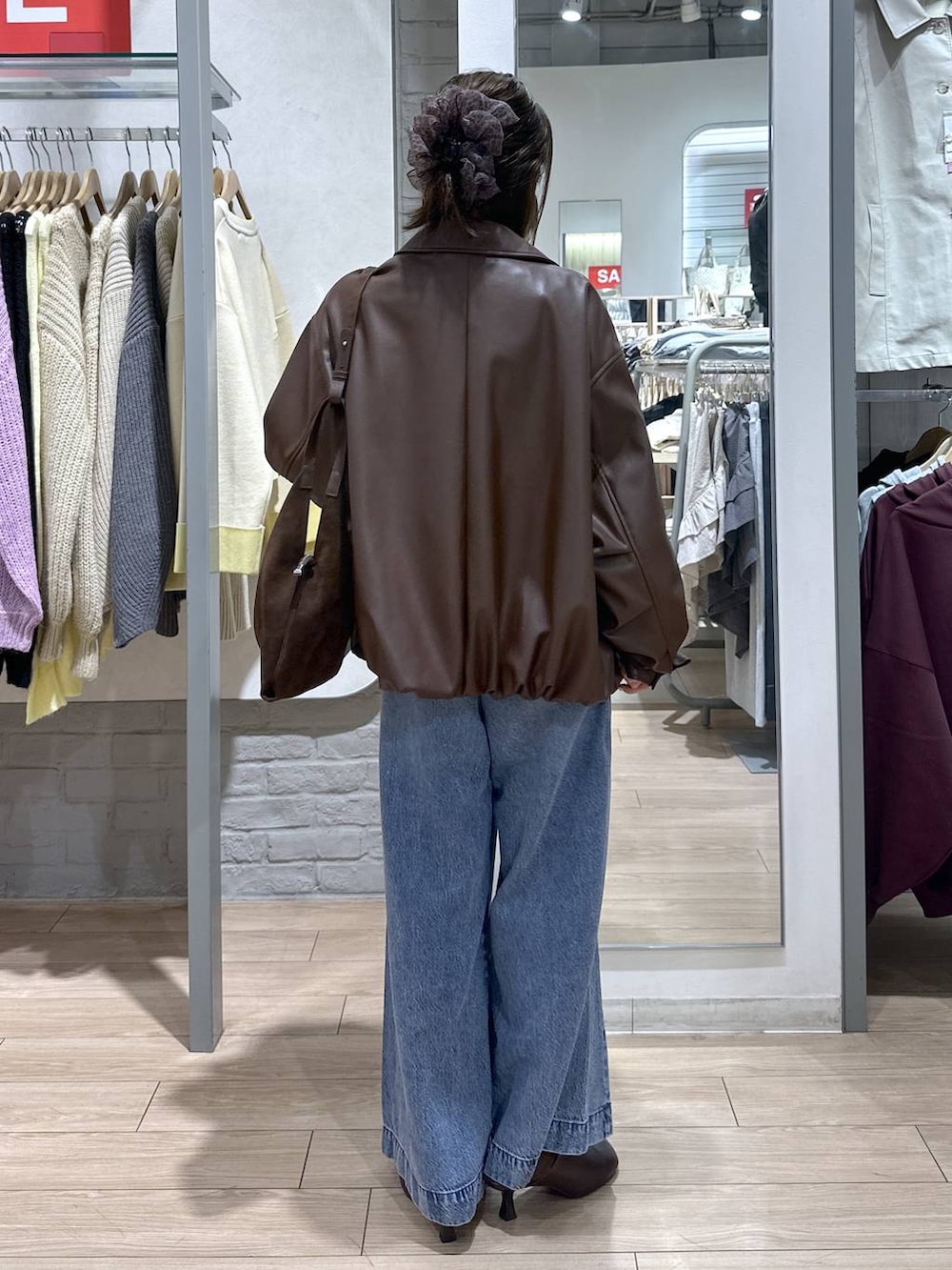 ブルー系のデニムパンツ、ブラウン系のブルゾン、ブラウン系のサンダルを着用したレディースの春コーディネートの5枚目の写真