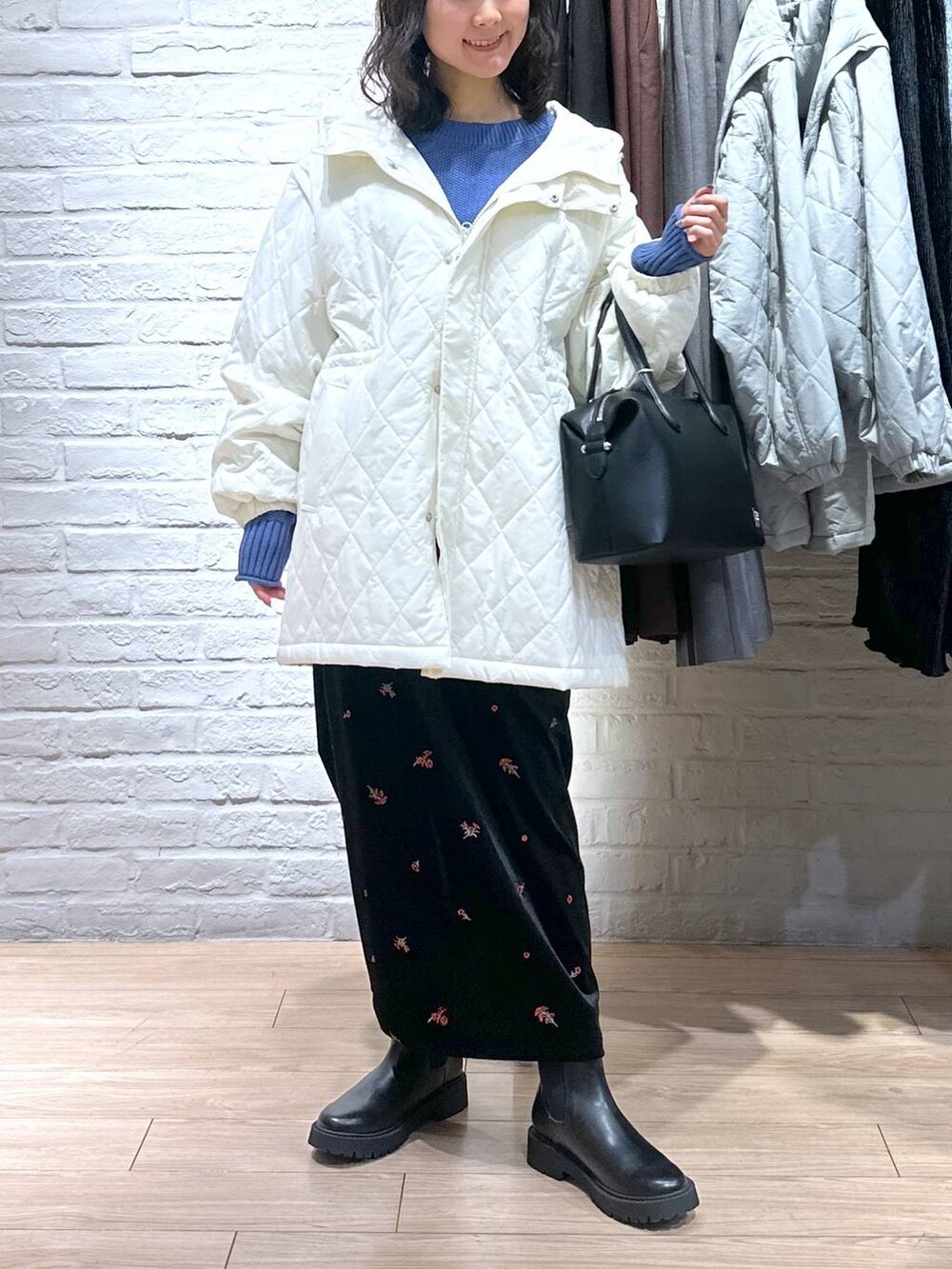 ブルー系のニット/セーター、ブラック系のブーツ、ホワイト系のブルゾンを着用したレディースの冬コーディネートの3枚目の写真