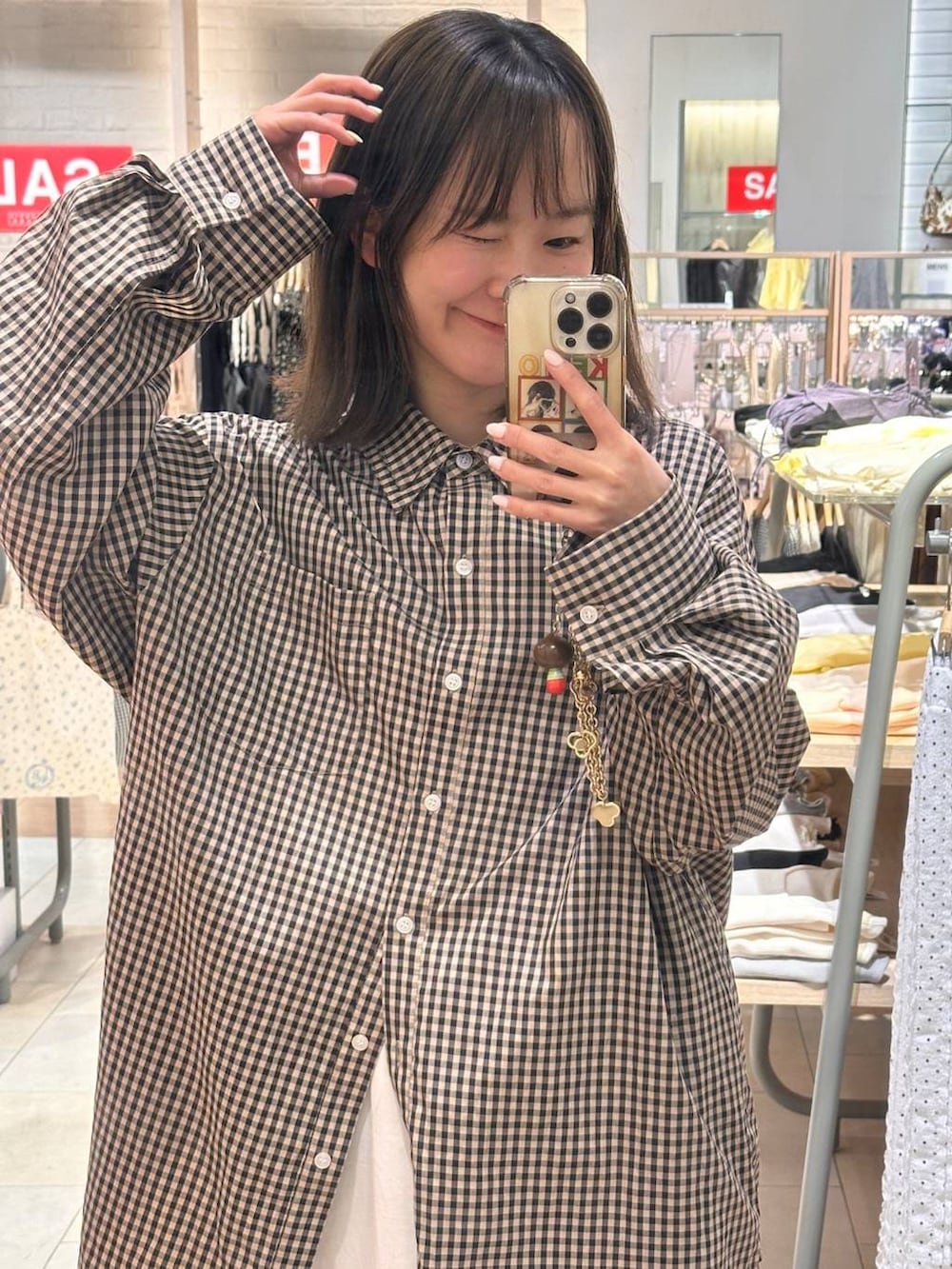 ピンク系のシャツ/ブラウス、ホワイト系のスカート、シルバー系のスニーカーを着用したレディースの春コーディネートの2枚目の写真