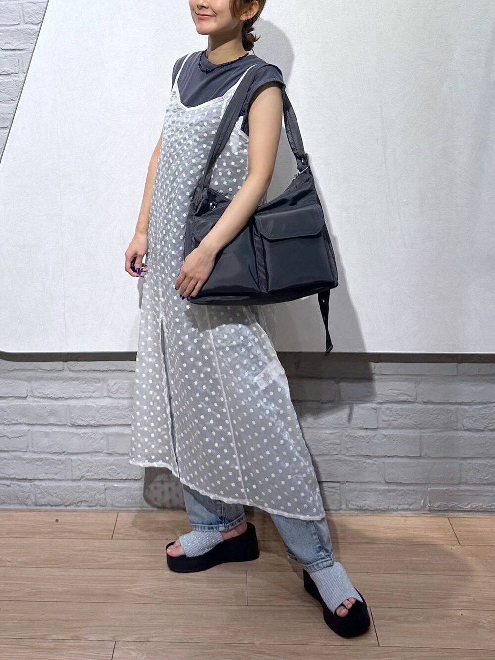 シルバー系のサンダル、ブルー系のデニムパンツ、ホワイト系のワンピースを着用したレディースの夏コーディネートの2枚目の写真