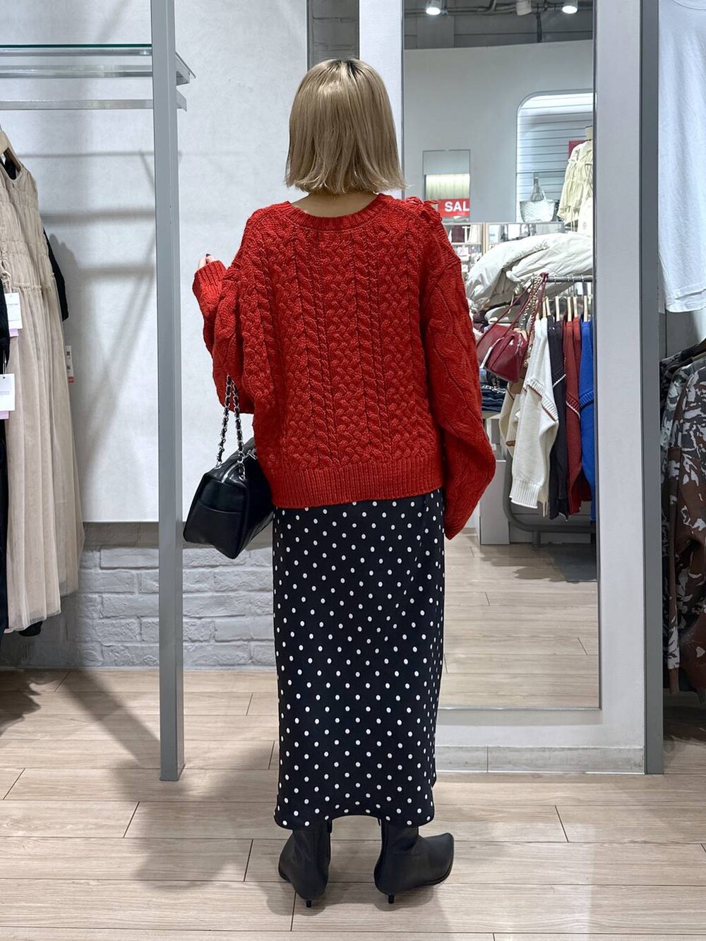 ブラック系のスカート、レッド系のポロシャツ、ブラック系のブーツを着用したレディースの冬コーディネートの5枚目の写真