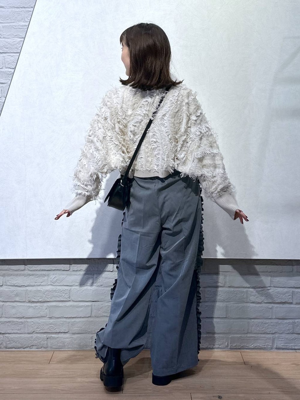 ブラック系のショルダーバッグ、ホワイト系のニット/セーター、ブラック系のブーツを着用したレディースの秋コーディネートの4枚目の写真