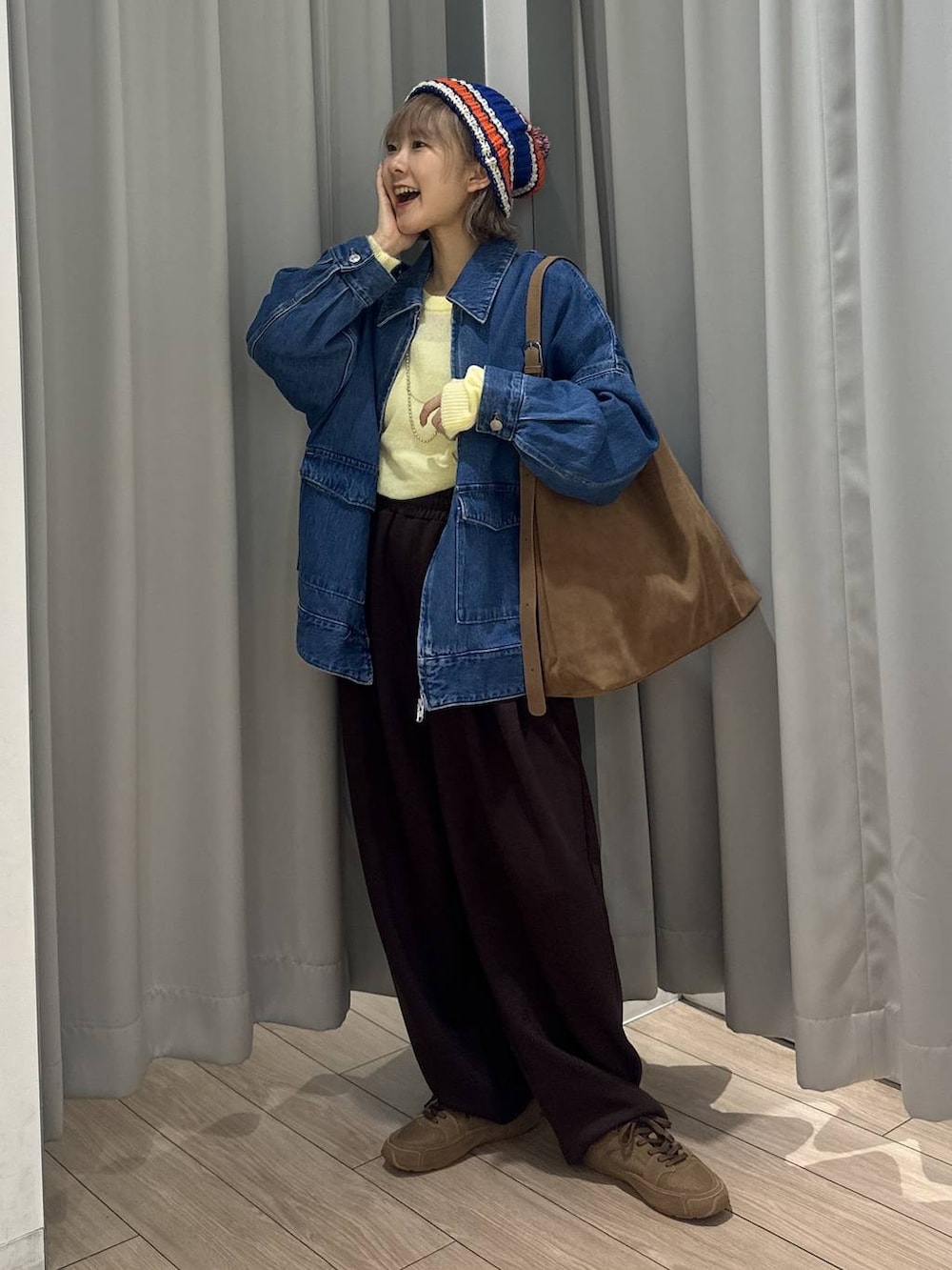 ベージュ系のショルダーバッグ、ブラウン系のスウェットパンツ、ブルー系のデニムジャケットを着用したレディースの秋コーディネートの4枚目の写真