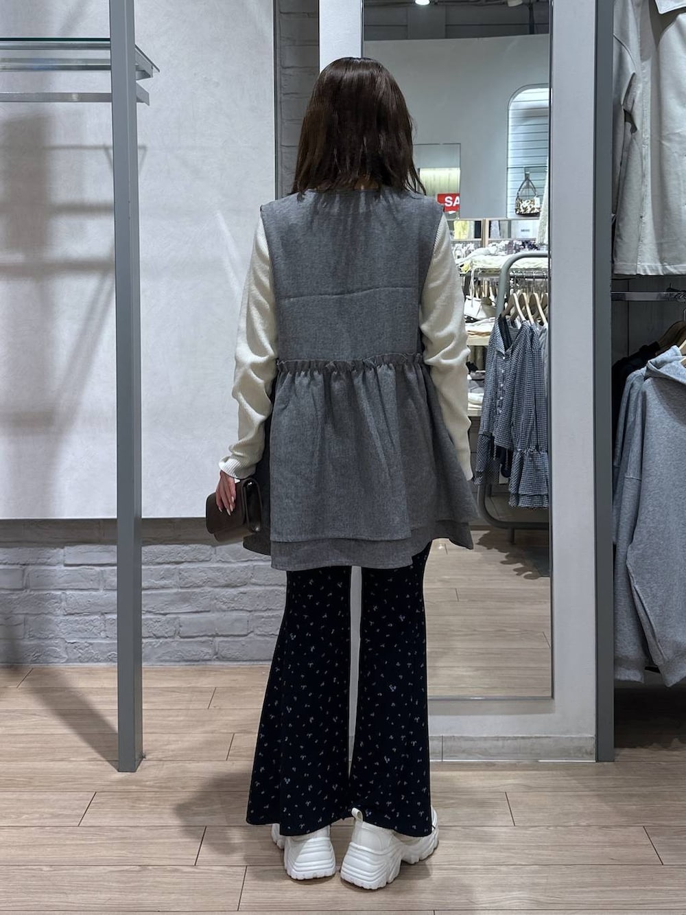 グレー系のベスト、ホワイト系のニット/セーター、ブラック系のボディバッグ/ウエストポーチを着用したレディースの春コーディネートの4枚目の写真