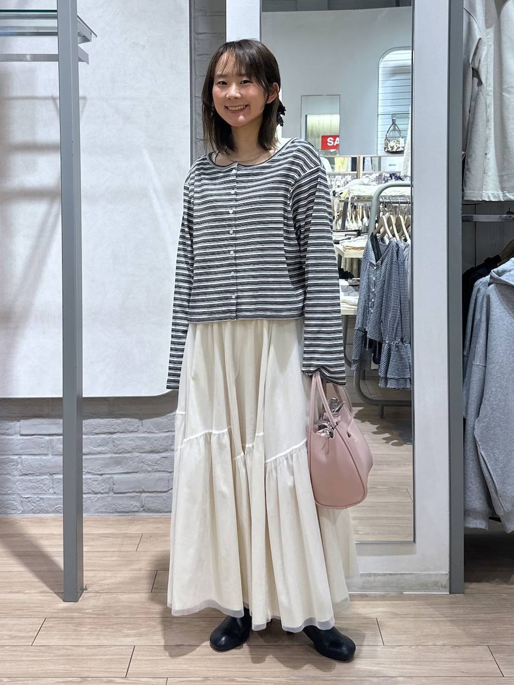 ピンク系のショルダーバッグ、ブラック系のサンダル、ホワイト系のニット/セーターを着用したレディースの春コーディネートの2枚目の写真