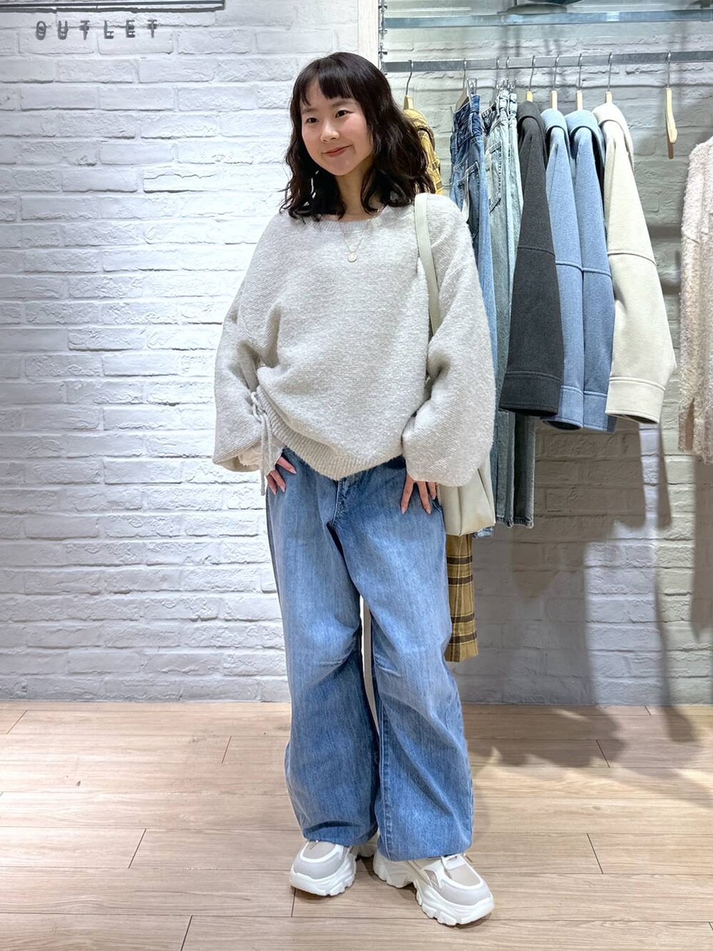 ブルー系のデニムパンツ、ホワイト系のショルダーバッグ、ベージュ系のスニーカーを着用したレディースの冬コーディネートの4枚目の写真