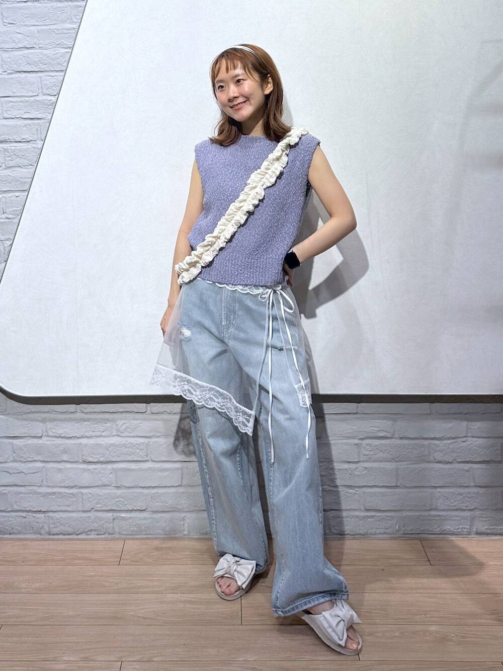 ホワイト系のサンダル、パープル系のベスト、ブルー系のデニムパンツを着用したレディースの夏コーディネートの5枚目の写真