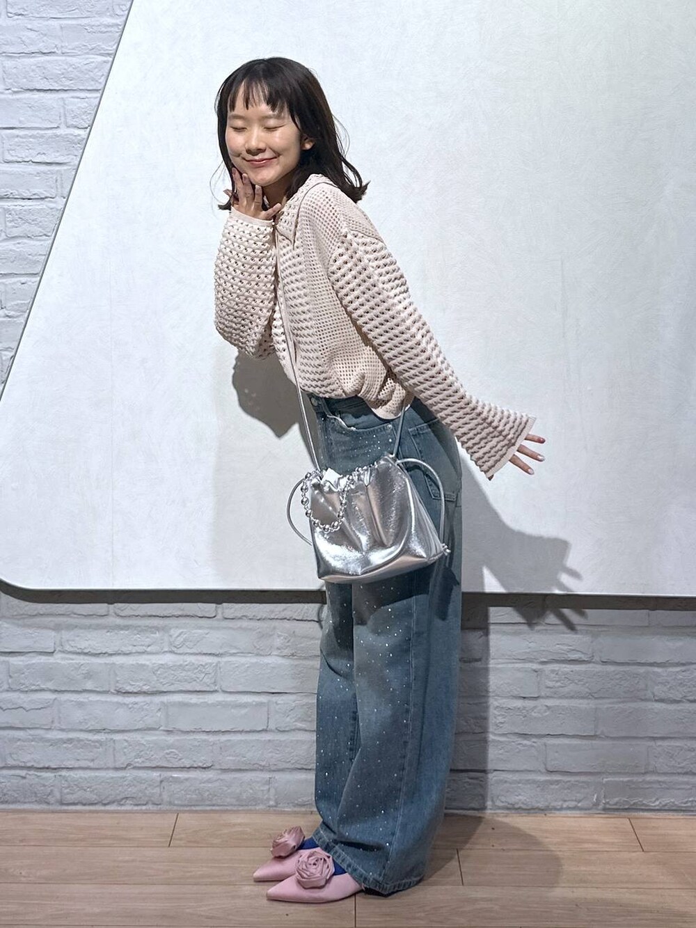 ピンク系のパンプス、シルバー系のショルダーバッグ、ブルー系のデニムパンツを着用したレディースの秋コーディネートの4枚目の写真