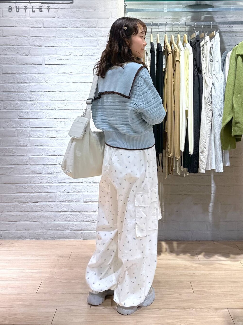 ベージュ系のショルダーバッグ、ホワイト系のTシャツ/カットソー、ブルー系のニット/セーターを着用したレディースの春コーディネートの3枚目の写真