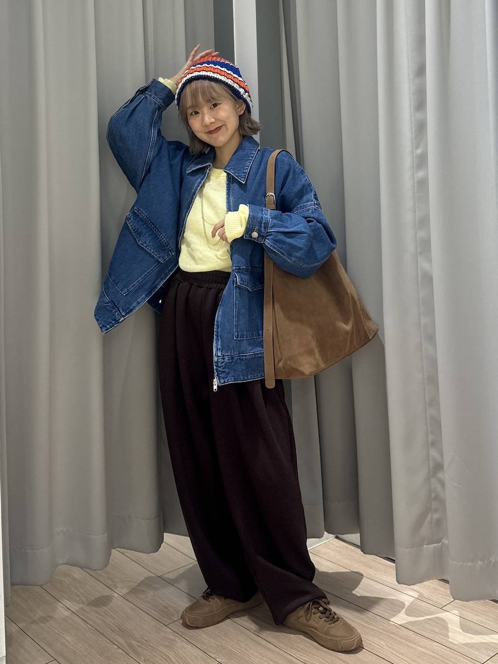 ベージュ系のショルダーバッグ、ブラウン系のスウェットパンツ、ブルー系のデニムジャケットを着用したレディースの秋コーディネートの2枚目の写真