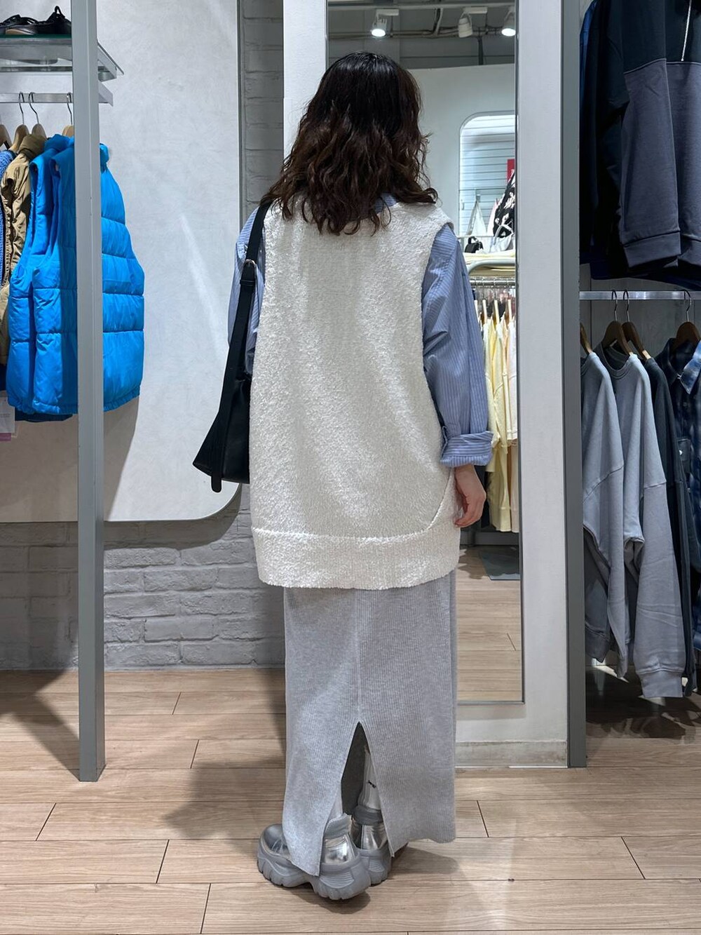 グレー系のスカート、ブルー系のシャツ/ブラウス、ホワイト系のニット/セーターを着用したレディースの春コーディネートの5枚目の写真
