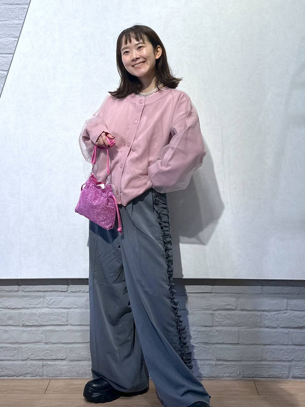 ピンク系のニット/セーター、ブラック系のブーツ、ピンク系のショルダーバッグを着用したレディースの秋コーディネートの2枚目の写真