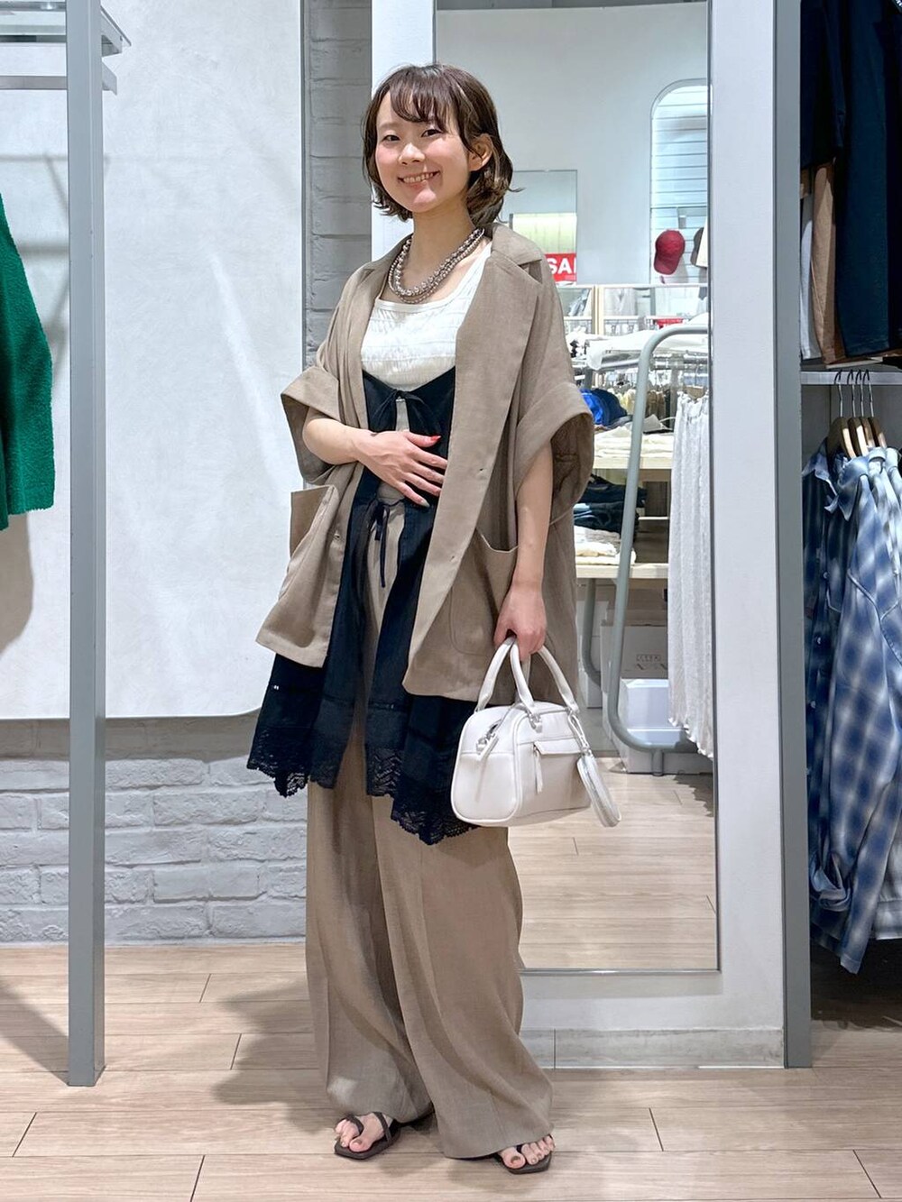 ホワイト系のタンクトップ、ブラウン系のサンダル、ベージュ系のテーラードジャケットを着用したレディースの夏コーディネートの2枚目の写真