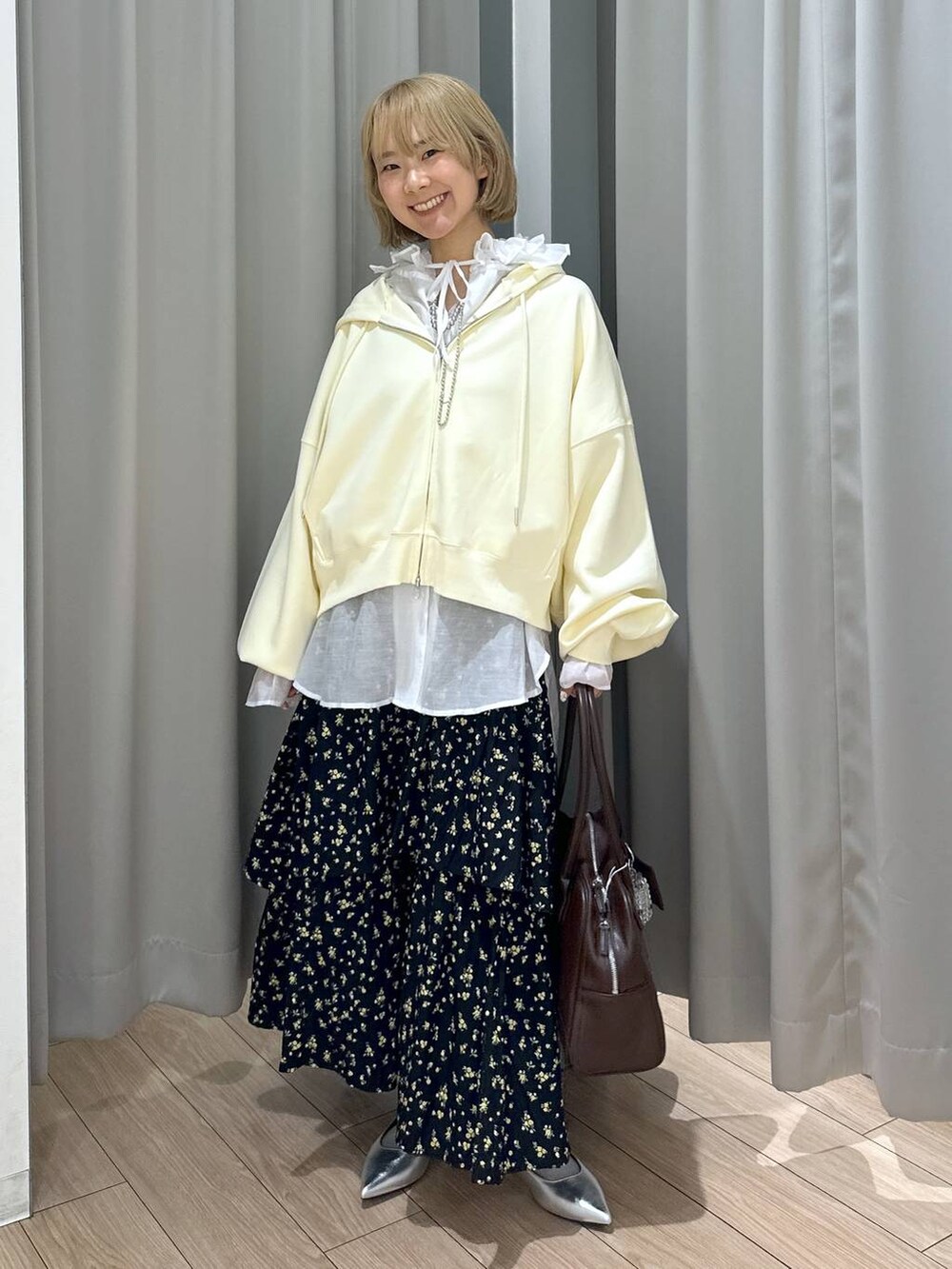 ブラウン系のボストンバッグ、ホワイト系のシャツ/ブラウス、シルバー系のパンプスを着用したレディースの秋コーディネートの2枚目の写真