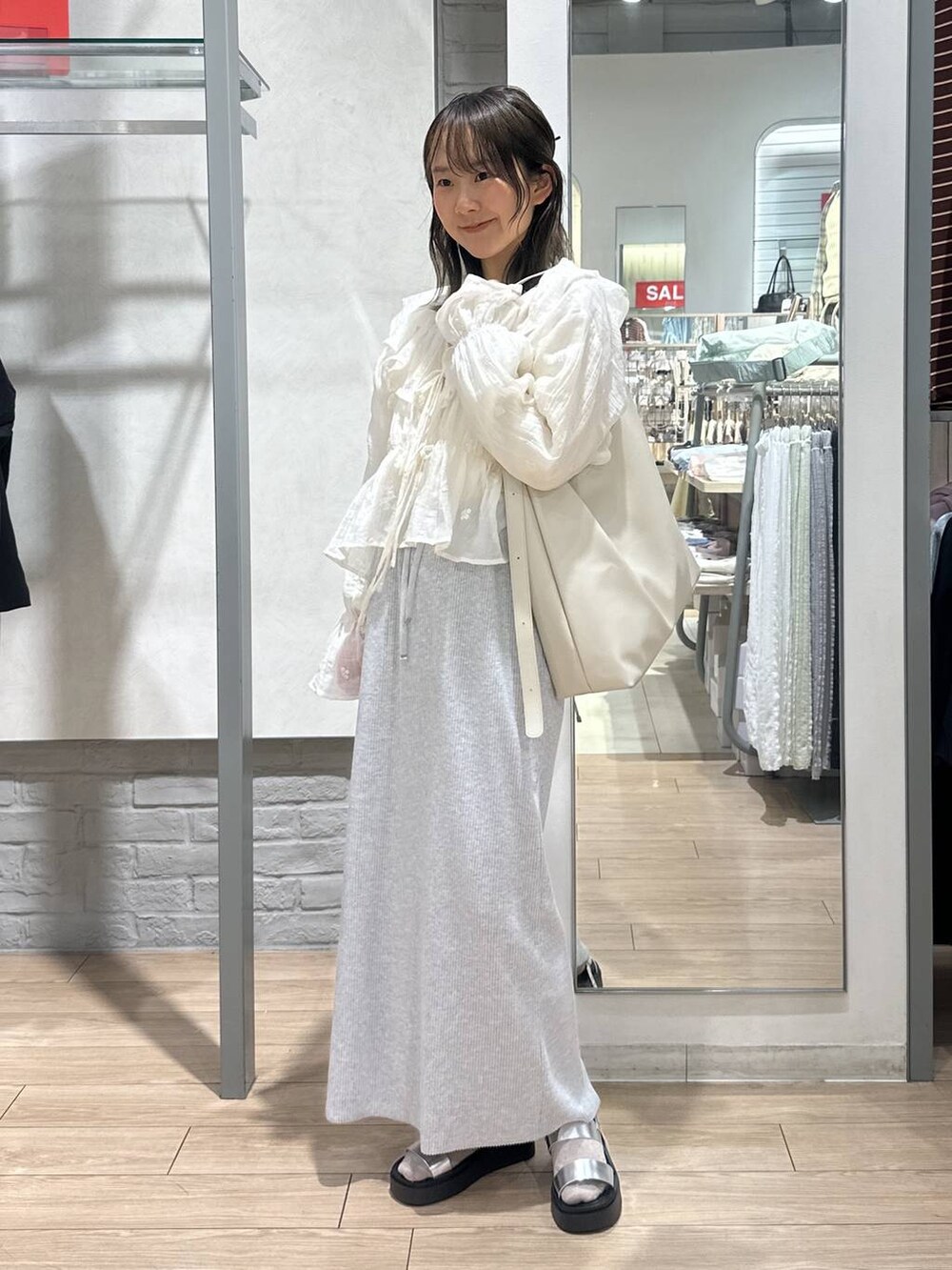 ベージュ系のTシャツ/カットソー、グレー系のスカート、ホワイト系のショルダーバッグを着用したレディースの春コーディネートの2枚目の写真