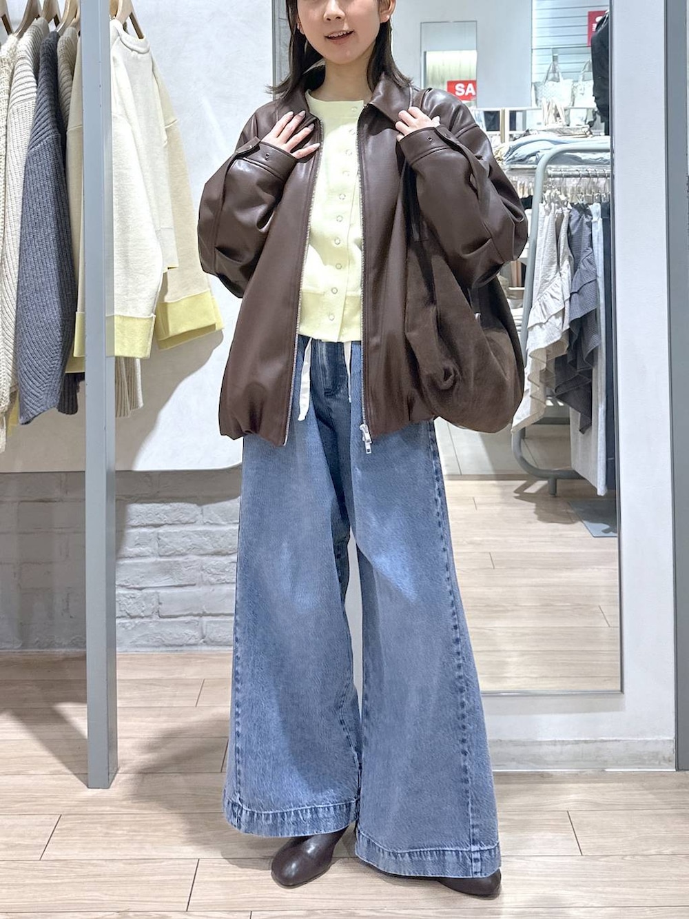 ブルー系のデニムパンツ、ブラウン系のブルゾン、ブラウン系のサンダルを着用したレディースの春コーディネートの4枚目の写真