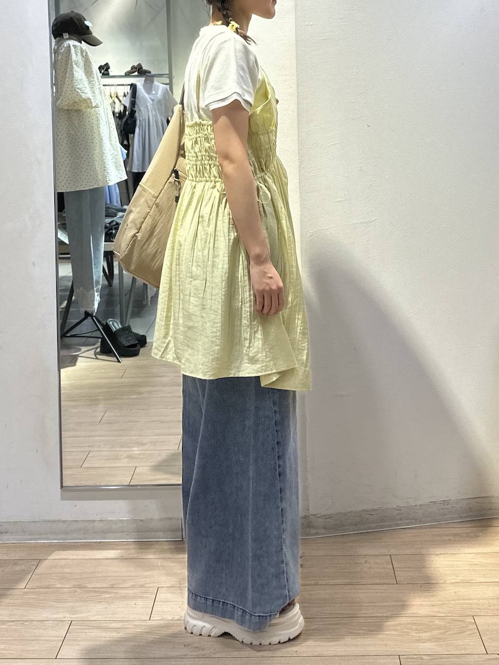 ベージュ系のショルダーバッグ、イエロー系のワンピース、ブルー系のデニムパンツを着用したレディースの夏コーディネートの3枚目の写真