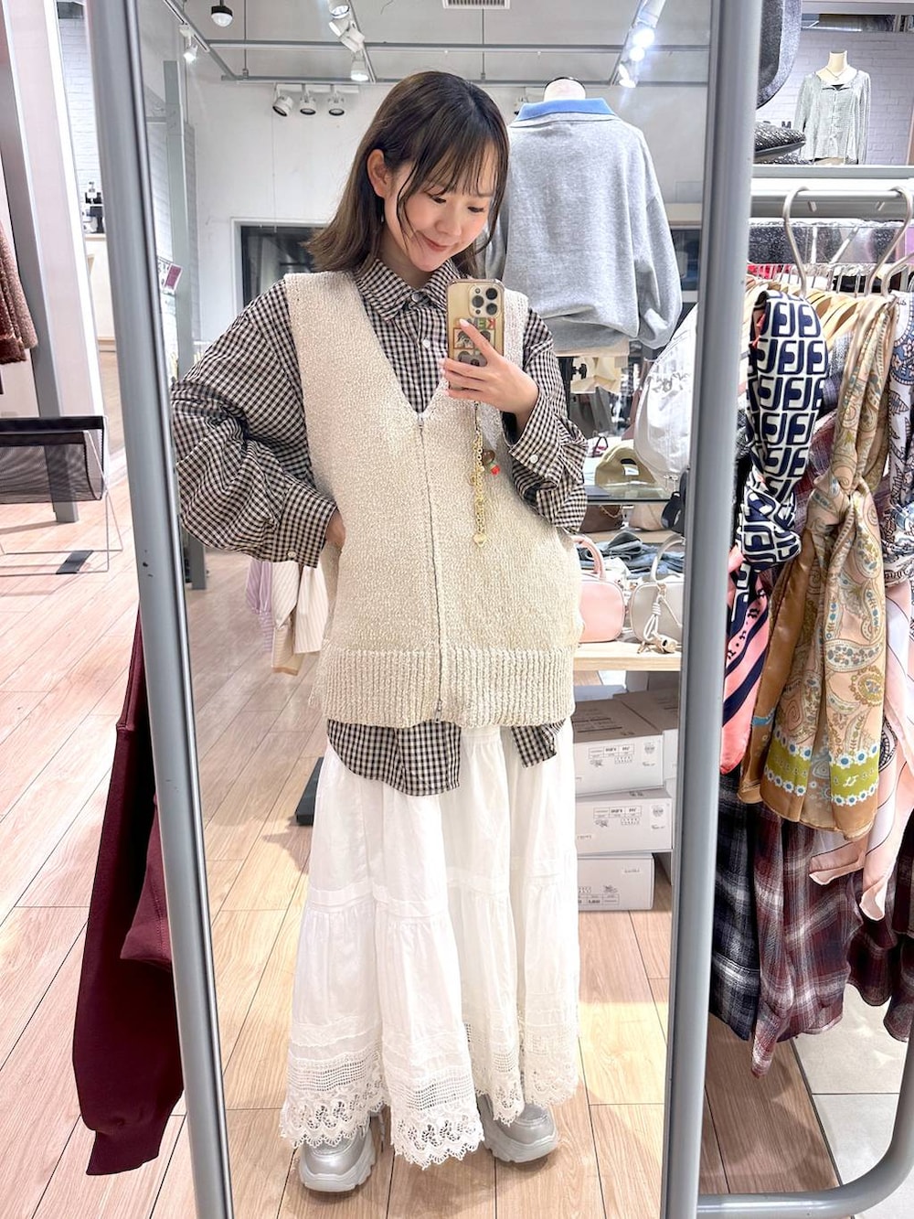 ブラウン系のシャツ/ブラウス、ベージュ系のベスト、ホワイト系のスカートを着用したレディースの春コーディネートの2枚目の写真