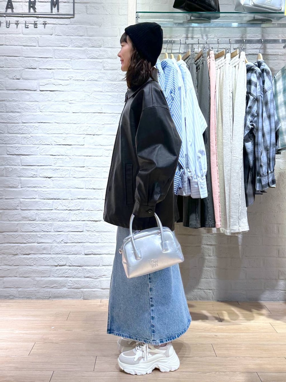 シルバー系のボストンバッグ、ベージュ系のスニーカー、ブラック系のブルゾンを着用したレディースの冬コーディネートの3枚目の写真