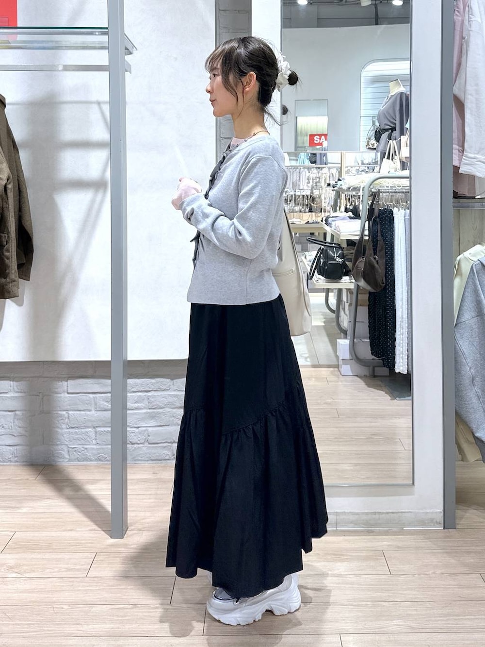 ホワイト系のショルダーバッグ、ピンク系のTシャツ/カットソー、ブラック系のスカートを着用したレディースの春コーディネートの3枚目の写真