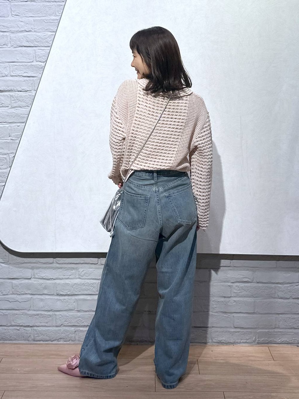ピンク系のパンプス、シルバー系のショルダーバッグ、ブルー系のデニムパンツを着用したレディースの秋コーディネートの3枚目の写真