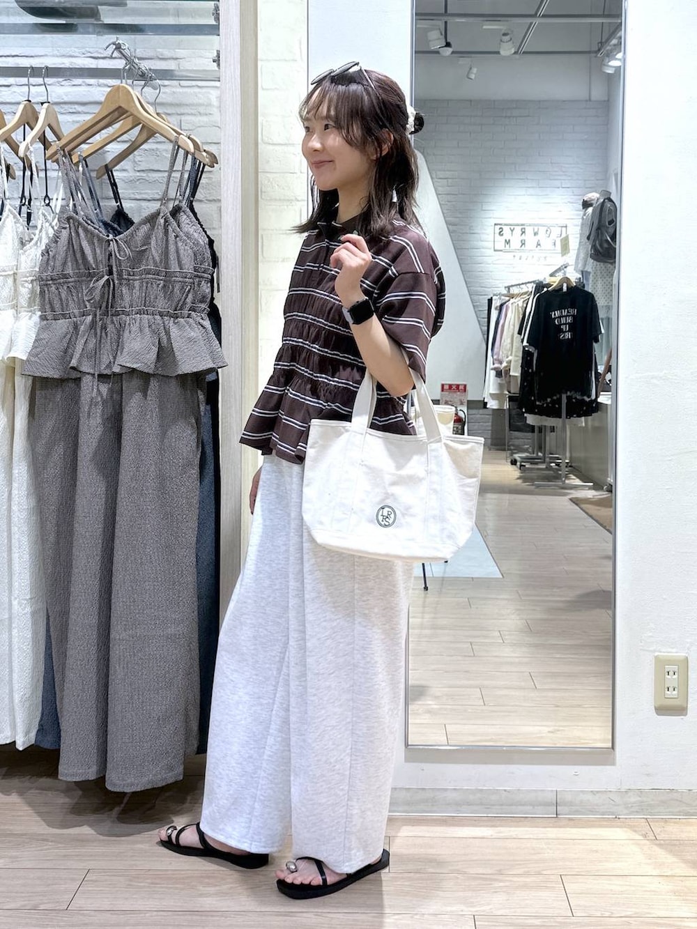 グレー系のスウェットパンツ、ホワイト系のショルダーバッグ、ブラック系のサンダルを着用したレディースの夏コーディネートの2枚目の写真