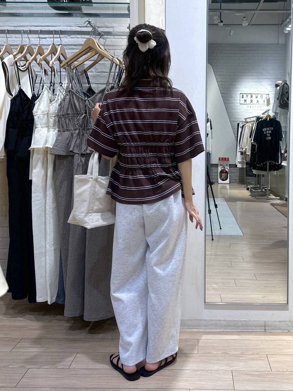グレー系のスウェットパンツ、ホワイト系のショルダーバッグ、ブラック系のサンダルを着用したレディースの夏コーディネートの4枚目の写真