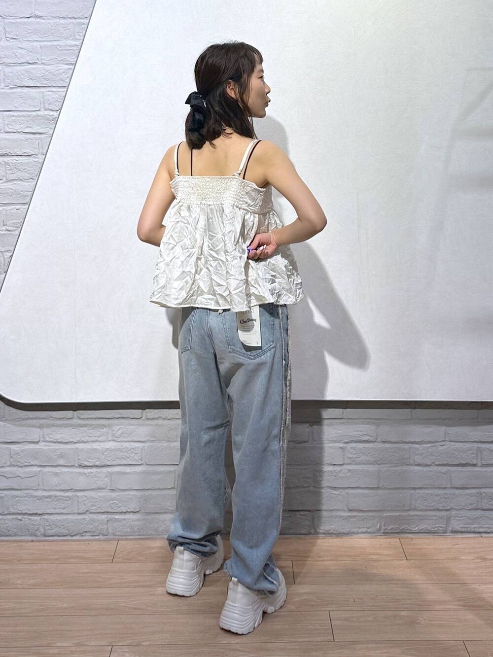 ホワイト系のスニーカー、ブラック系のキャミソール、ホワイト系のボストンバッグを着用したレディースの秋コーディネートの3枚目の写真