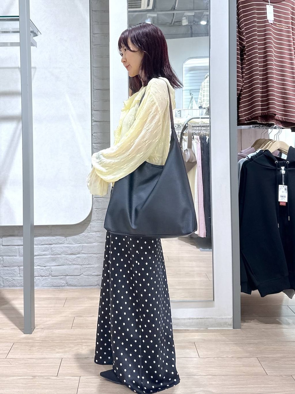 ブラック系のショルダーバッグ、ブラック系のスカート、ブラック系のパンプスを着用したレディースの春コーディネートの2枚目の写真
