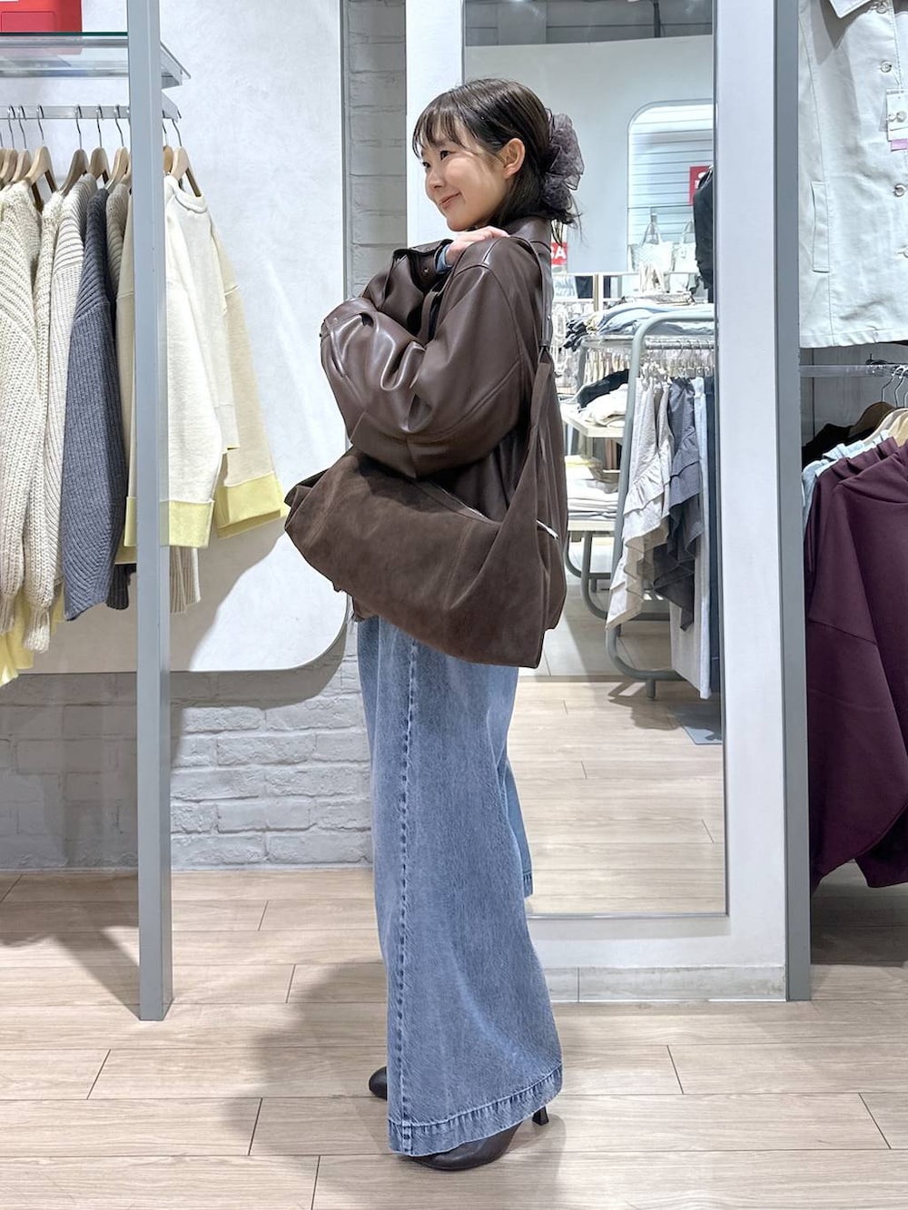 ブルー系のデニムパンツ、ブラウン系のブルゾン、ブラウン系のサンダルを着用したレディースの春コーディネートの2枚目の写真