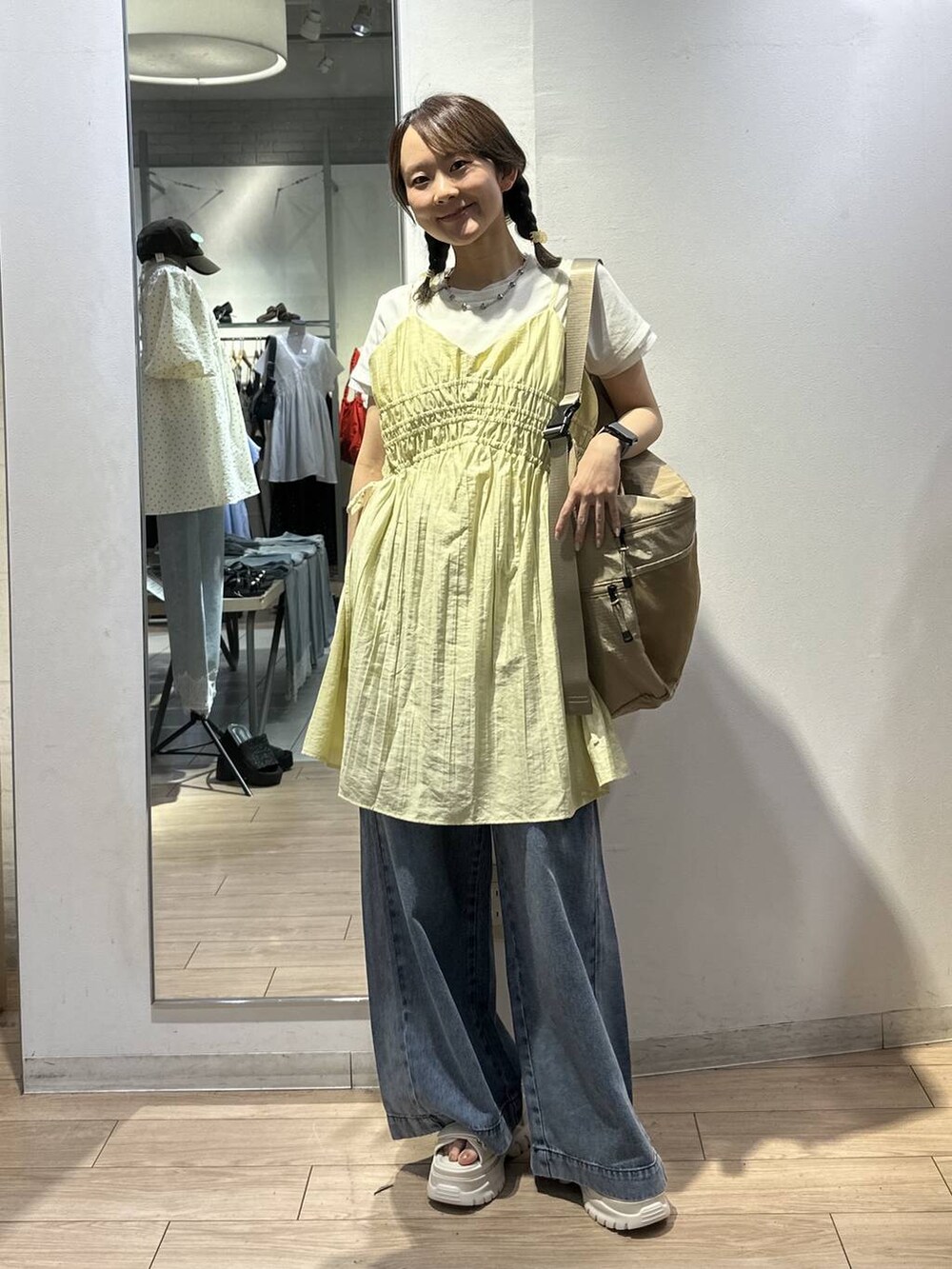 ベージュ系のショルダーバッグ、イエロー系のワンピース、ブルー系のデニムパンツを着用したレディースの夏コーディネートの5枚目の写真