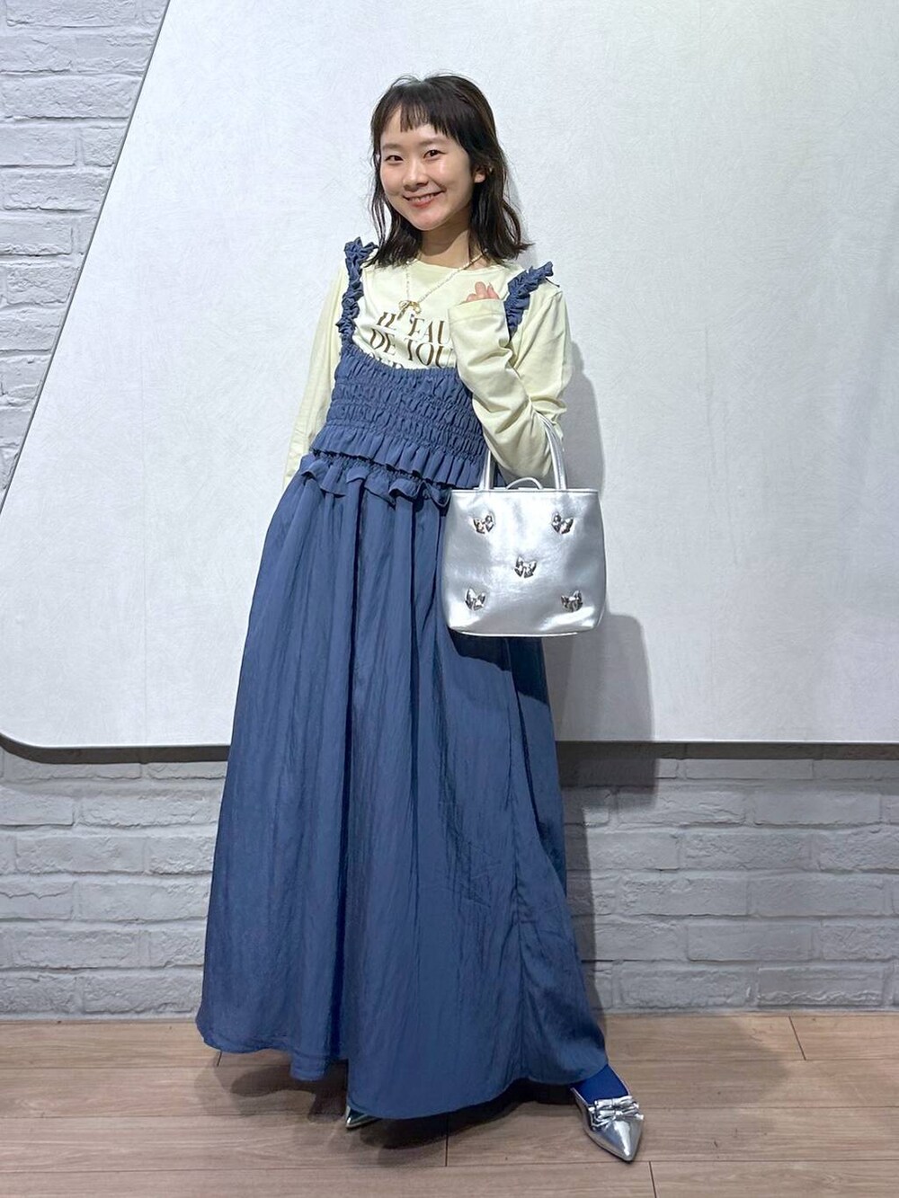 シルバー系のショルダーバッグ、シルバー系のパンプス、イエロー系のTシャツ/カットソーを着用したレディースの夏コーディネートの4枚目の写真