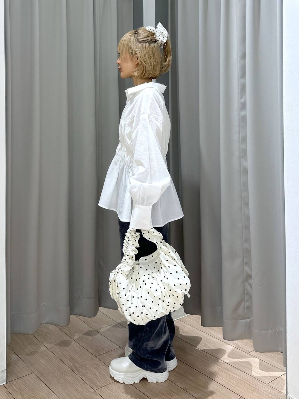 ホワイト系のブーツ、グレー系のデニムパンツ、ホワイト系のショルダーバッグを着用したレディースの秋コーディネートの3枚目の写真